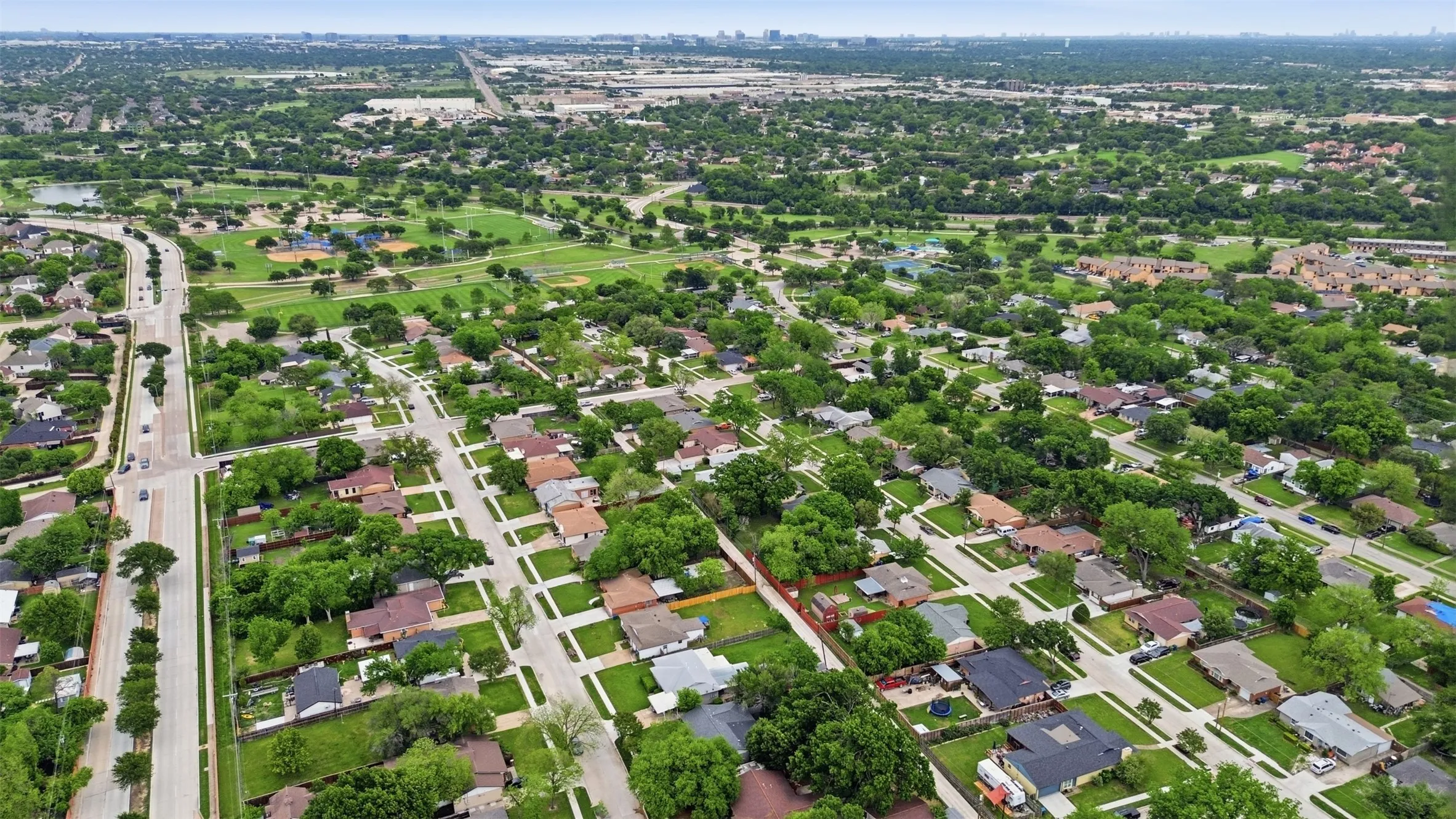 Residential neighborhood with mature trees, green spaces, and paved streets