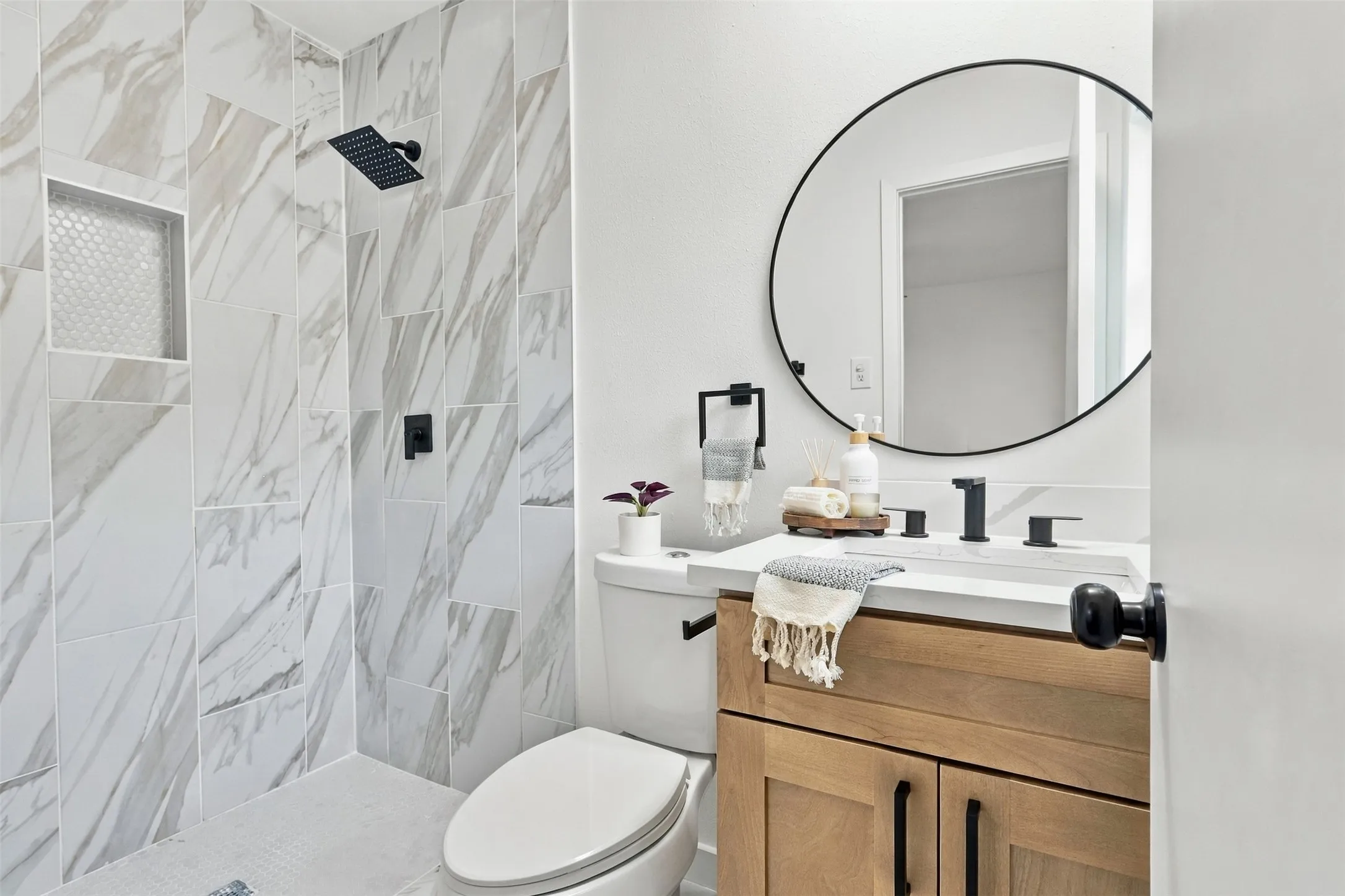 Tiled shower with a recessed niche and black rain shower head