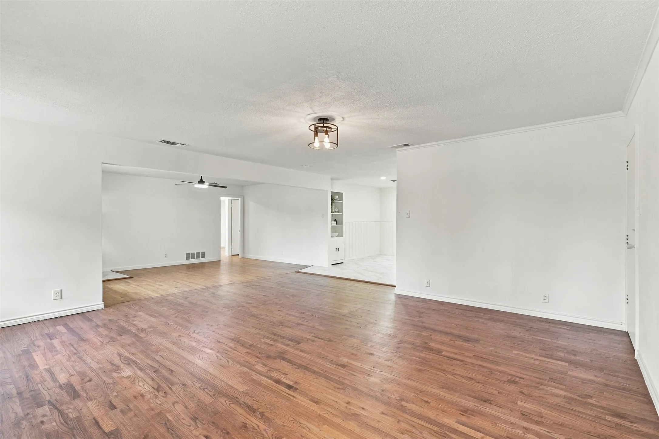 Hardwood flooring throughout, recessed built-in shelving, ceiling fan, and contemporary flush mount light fixture