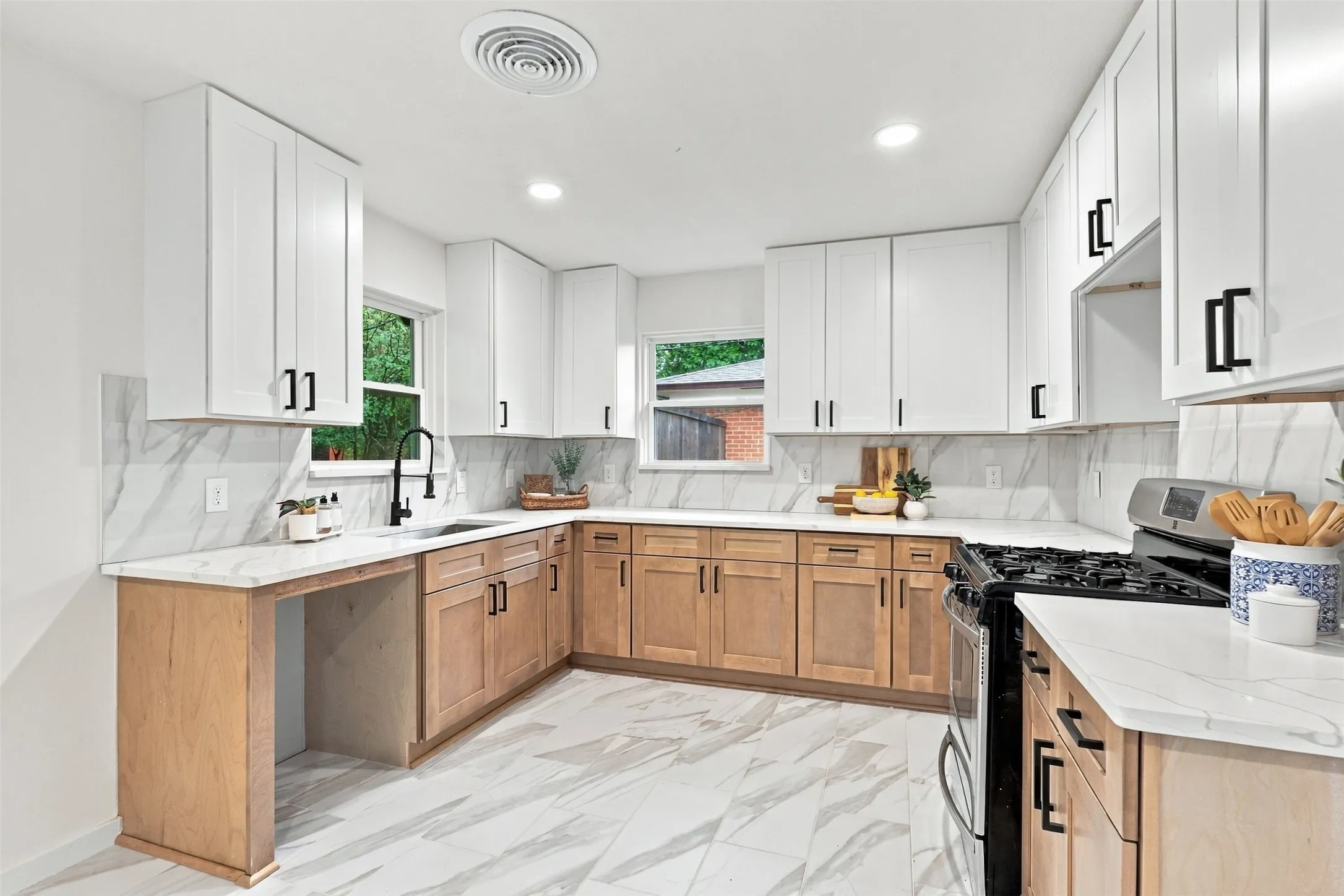 Kitchen featuring white upper cabinetry, wood-finish lower cabinetry, and black hardware
