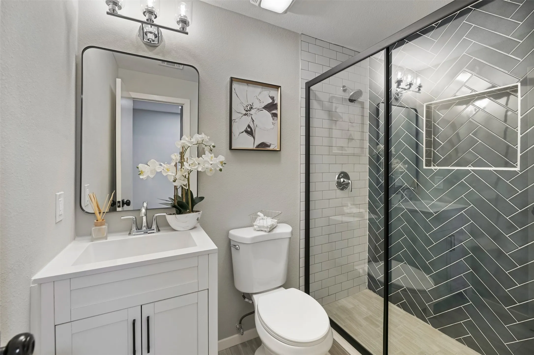 Primary Bathroom with a new vanity, toilet, light fixture, shower door and tile surround