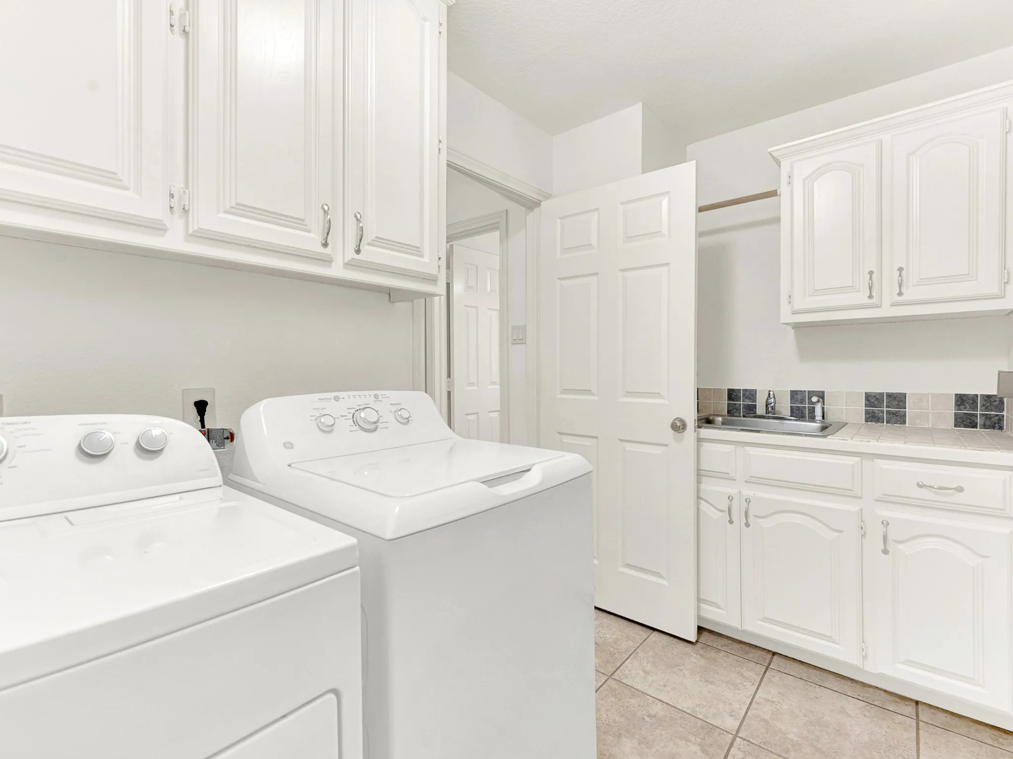 Large laundry room with a sink, extra cabinet and counter space
