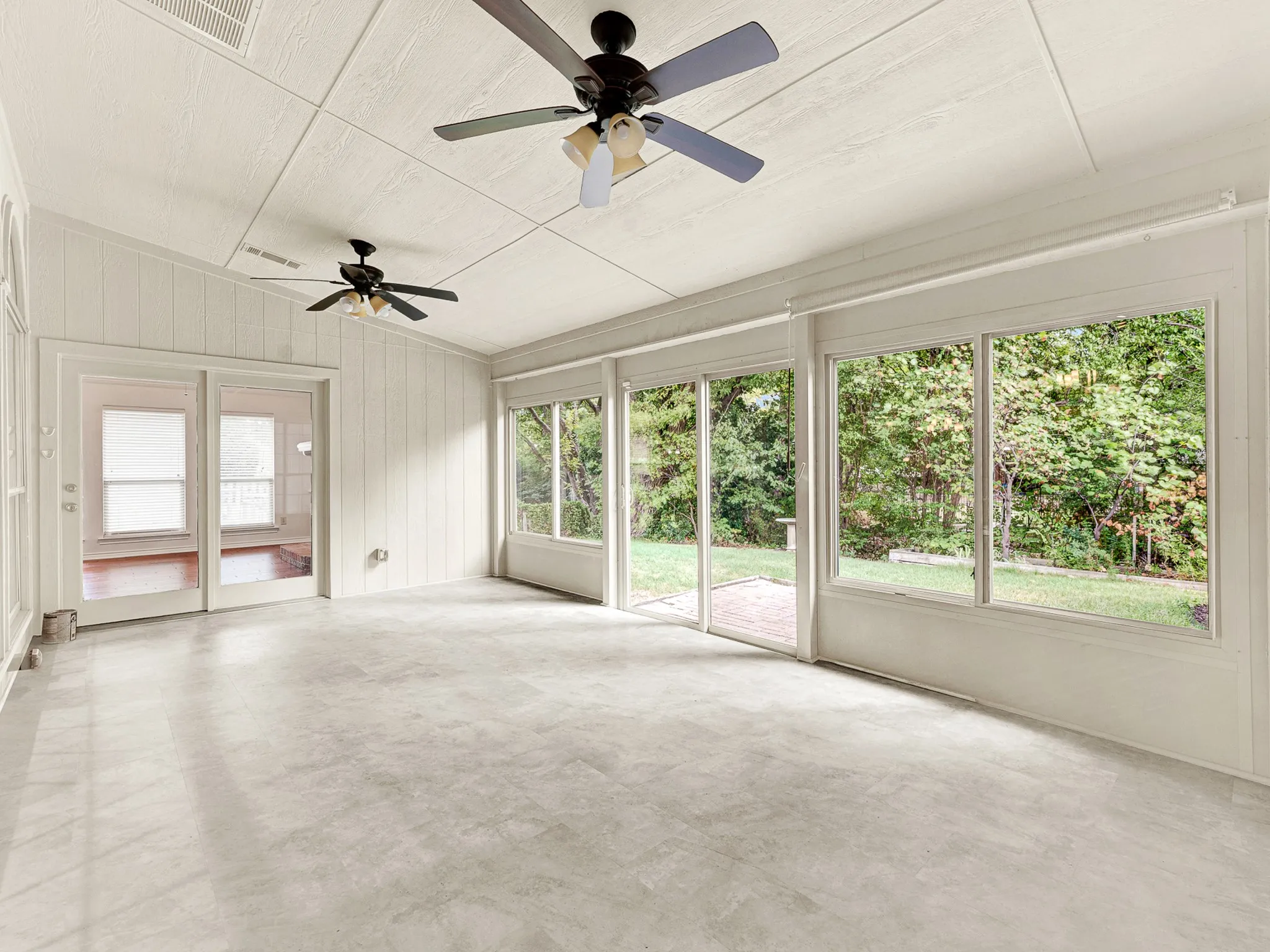 Enclosed sunroom / flex space features a wall of windows overlooking the private backyard