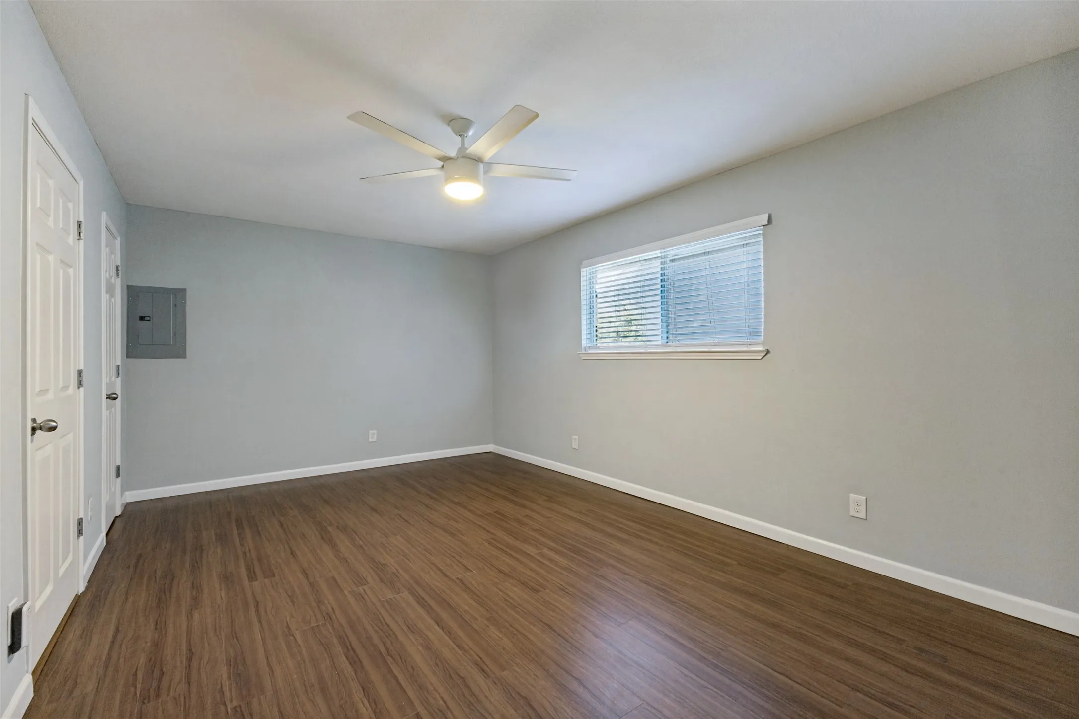 Wood-finish flooring, white trim, recessed window, and overhead ceiling fan with integrated lighting