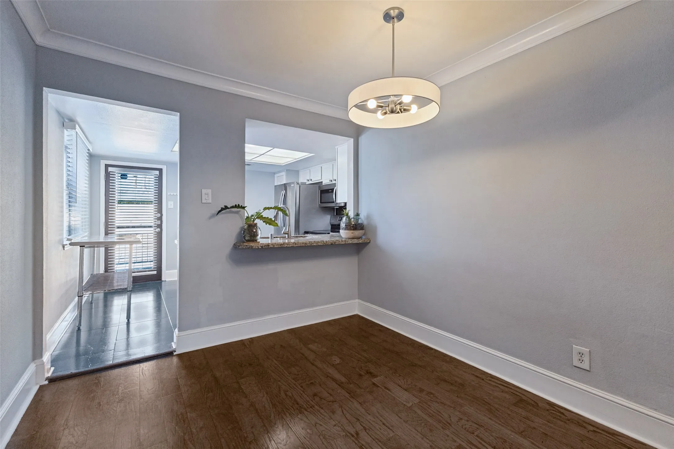 Wood-finish flooring, crown molding, and a modern chandelier