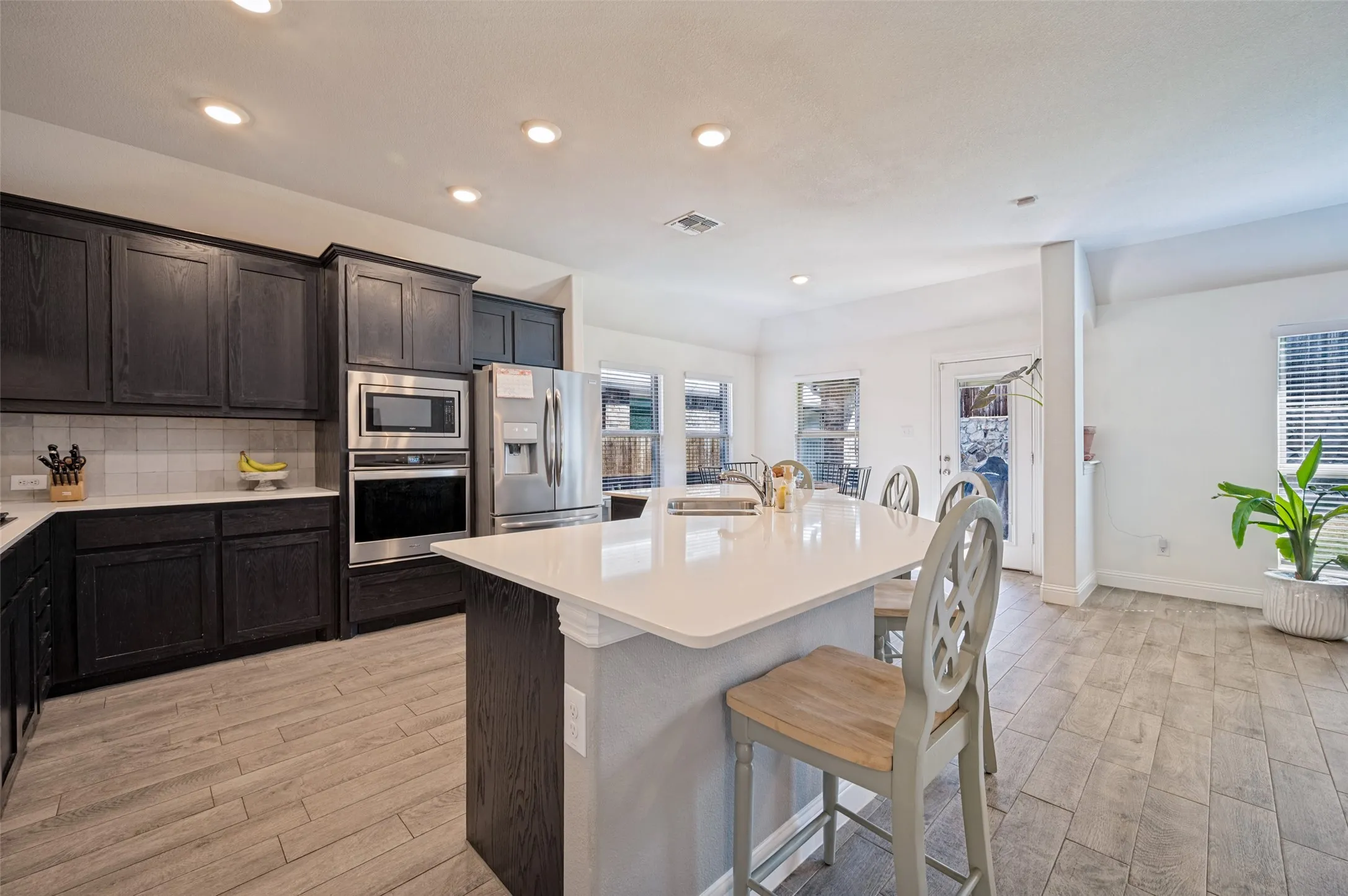 Kitchen featuring dark wood cabinetry, stainless steel appliances, a center island with countertop seating, and light wood-finish flooring