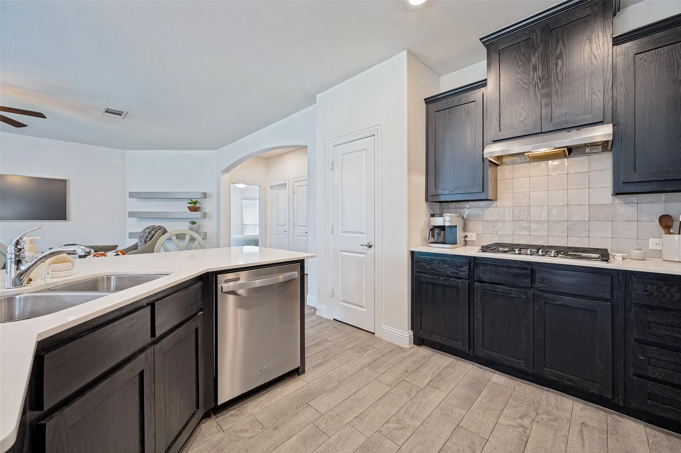 Kitchen featuring dark wood-finish cabinetry, stainless steel appliances, light countertops, and a subway tile backsplash