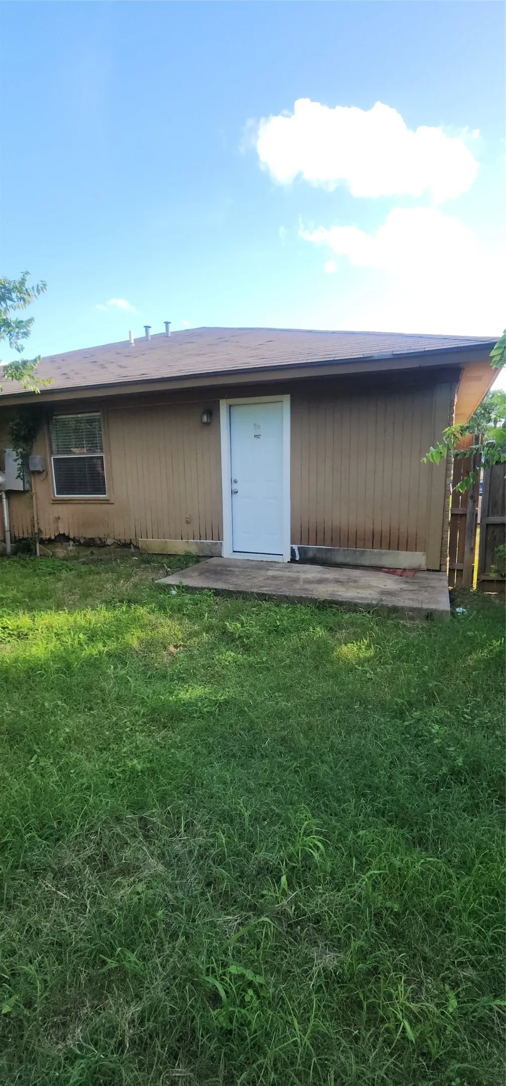 Brown siding exterior with a white entry door, an exterior light fixture, and a single window
