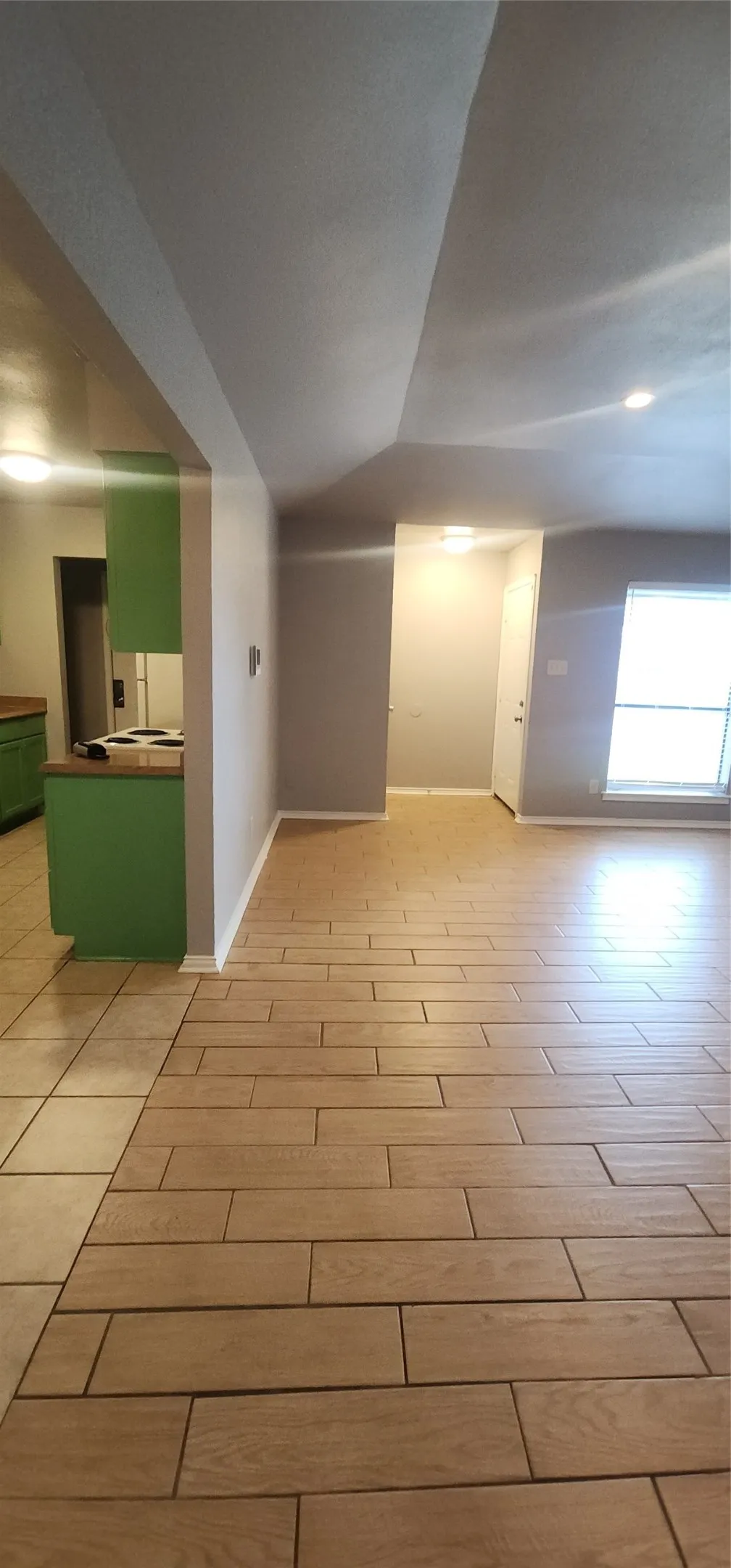 Wood-finish tile flooring, recessed lighting, and green cabinetry with a light-colored countertop