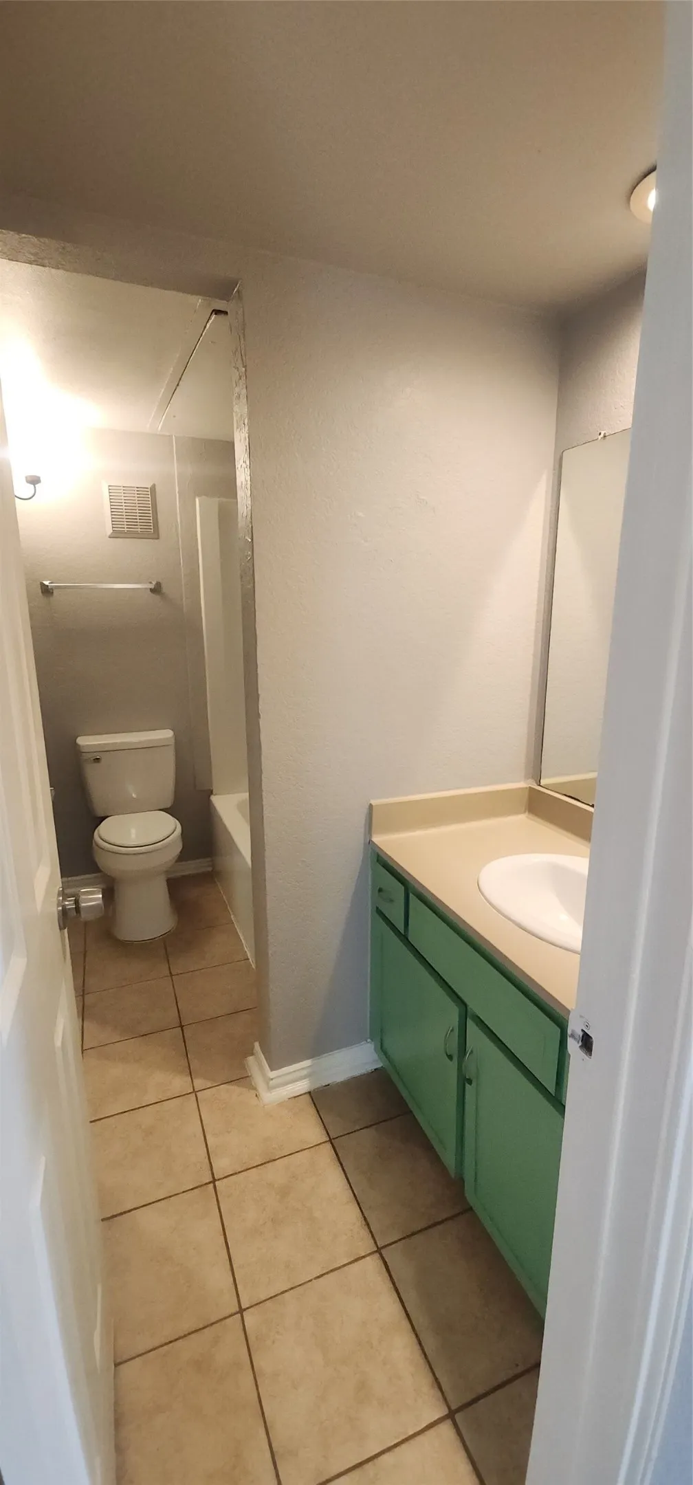 Bathroom featuring a single vanity with a white basin sink, green cabinetry, and a beige countertop