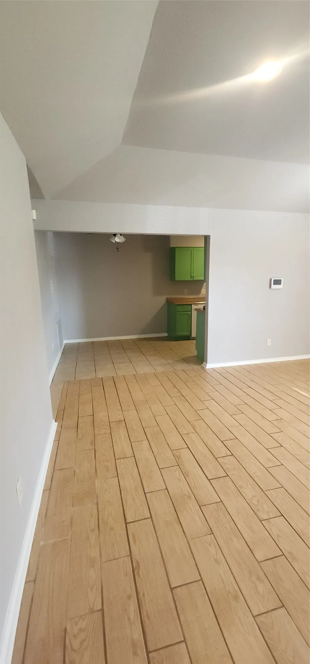 Wood-finish flooring throughout, featuring a vaulted ceiling and recessed lighting