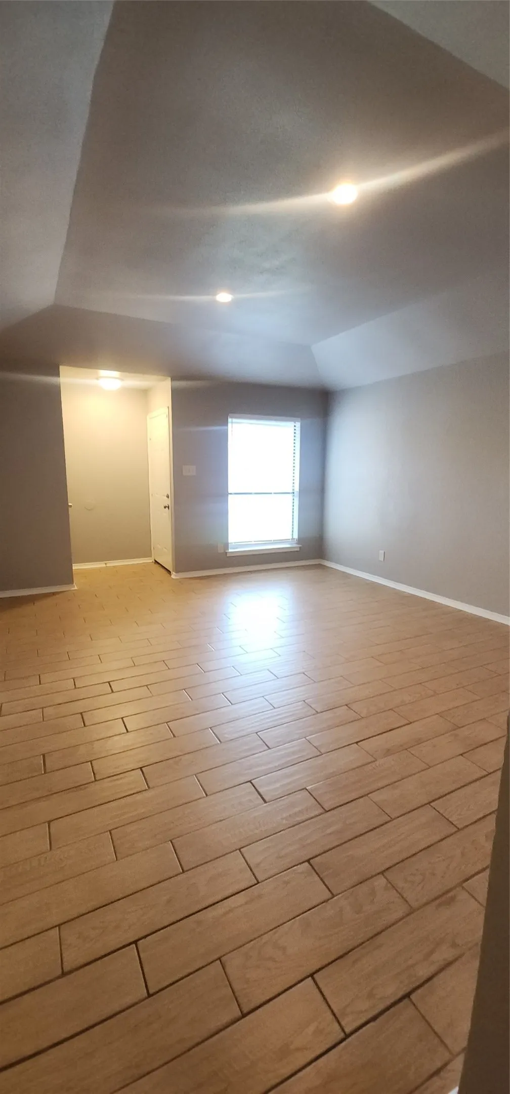 Spacious room featuring wood-finish tile flooring, recessed lighting, and a prominent window
