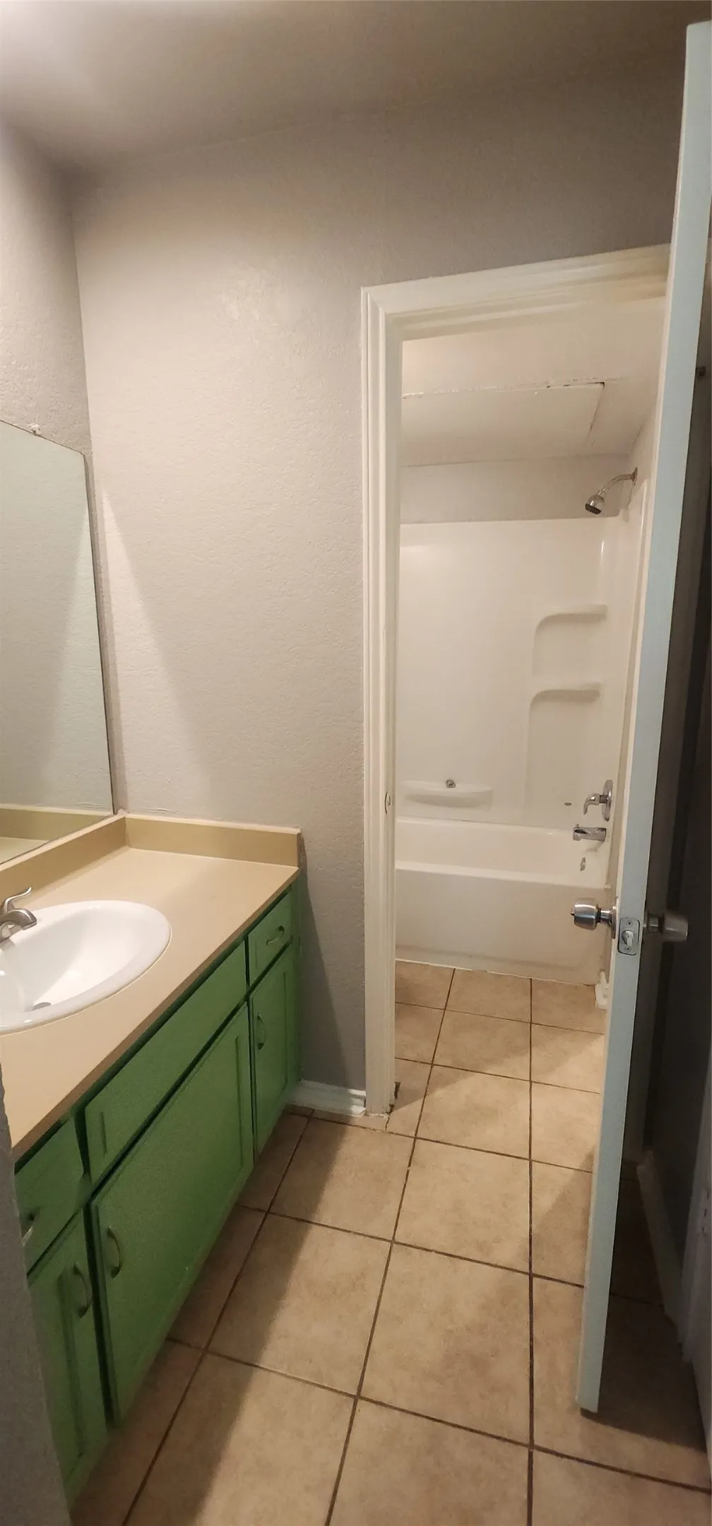 Bathroom featuring a single vanity with a green cabinet, a rectangular sink, and a tan countertop