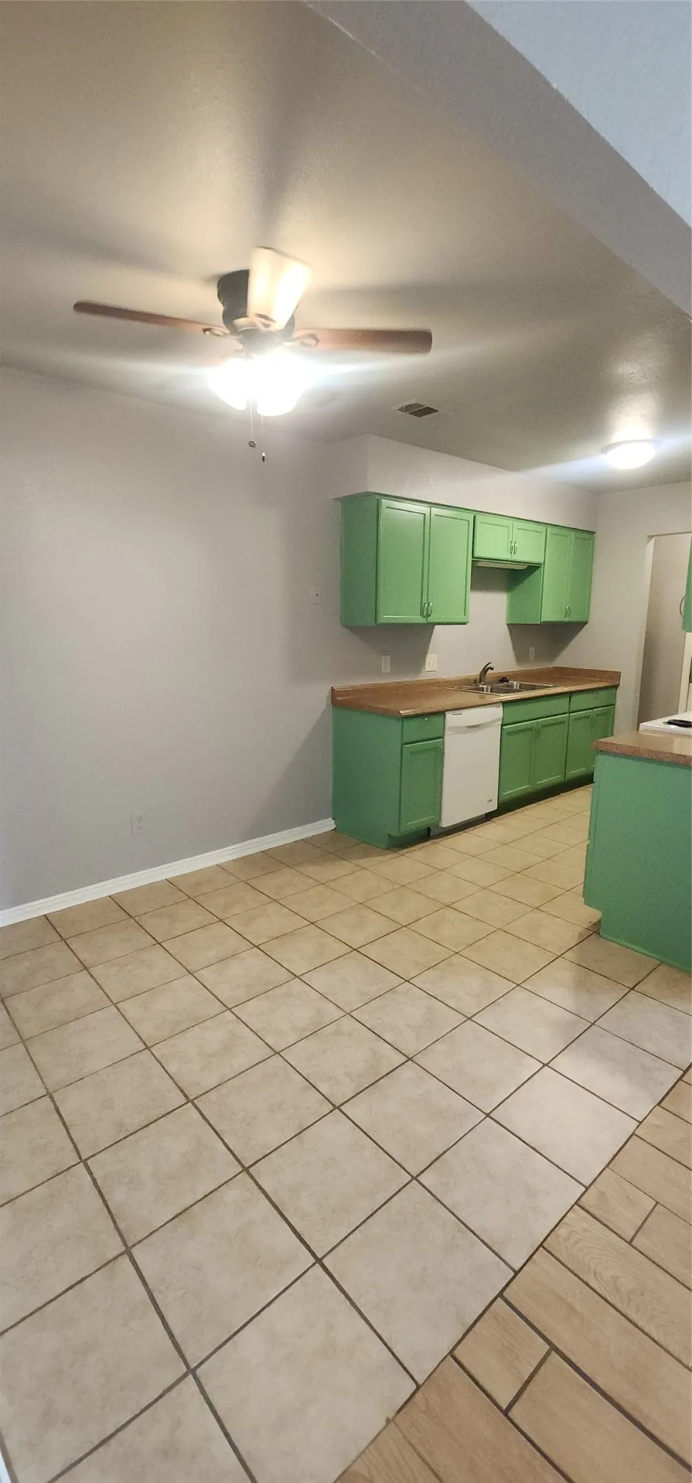 Kitchen featuring green cabinetry, wood-finish countertops, and tile flooring