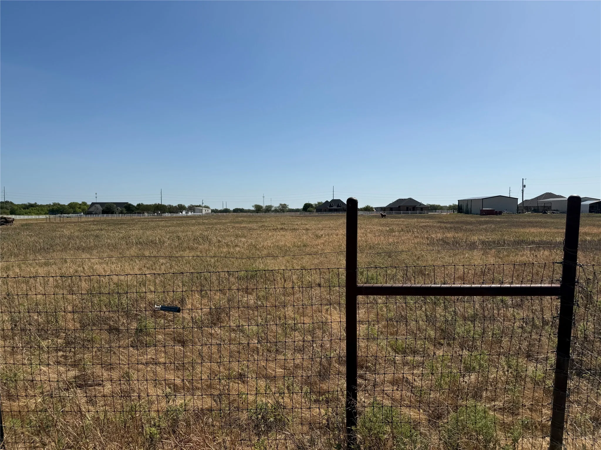 Expansive open land with a wire fence and metal gate