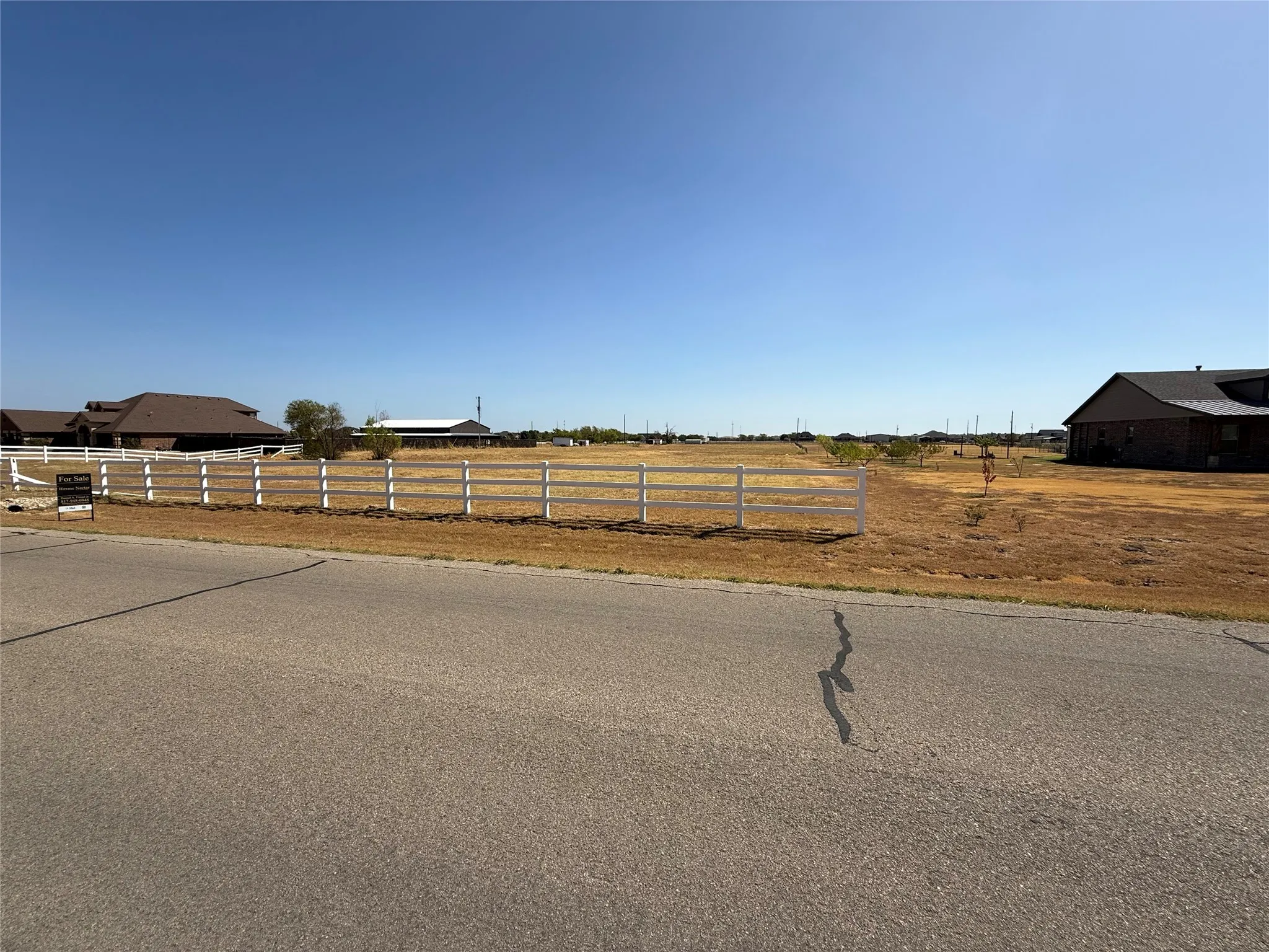 Expansive land parcel featuring a white fence boundary