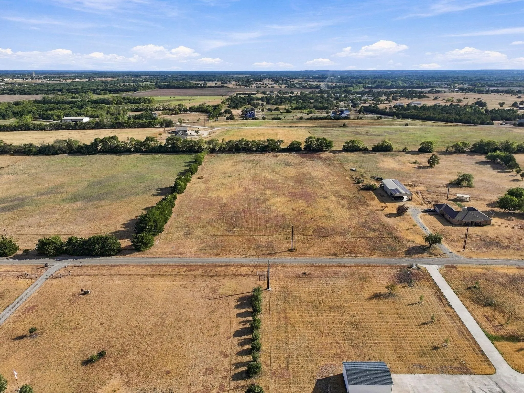 Expansive land parcels with clear boundaries, established road access, mature tree lines, and distant structures