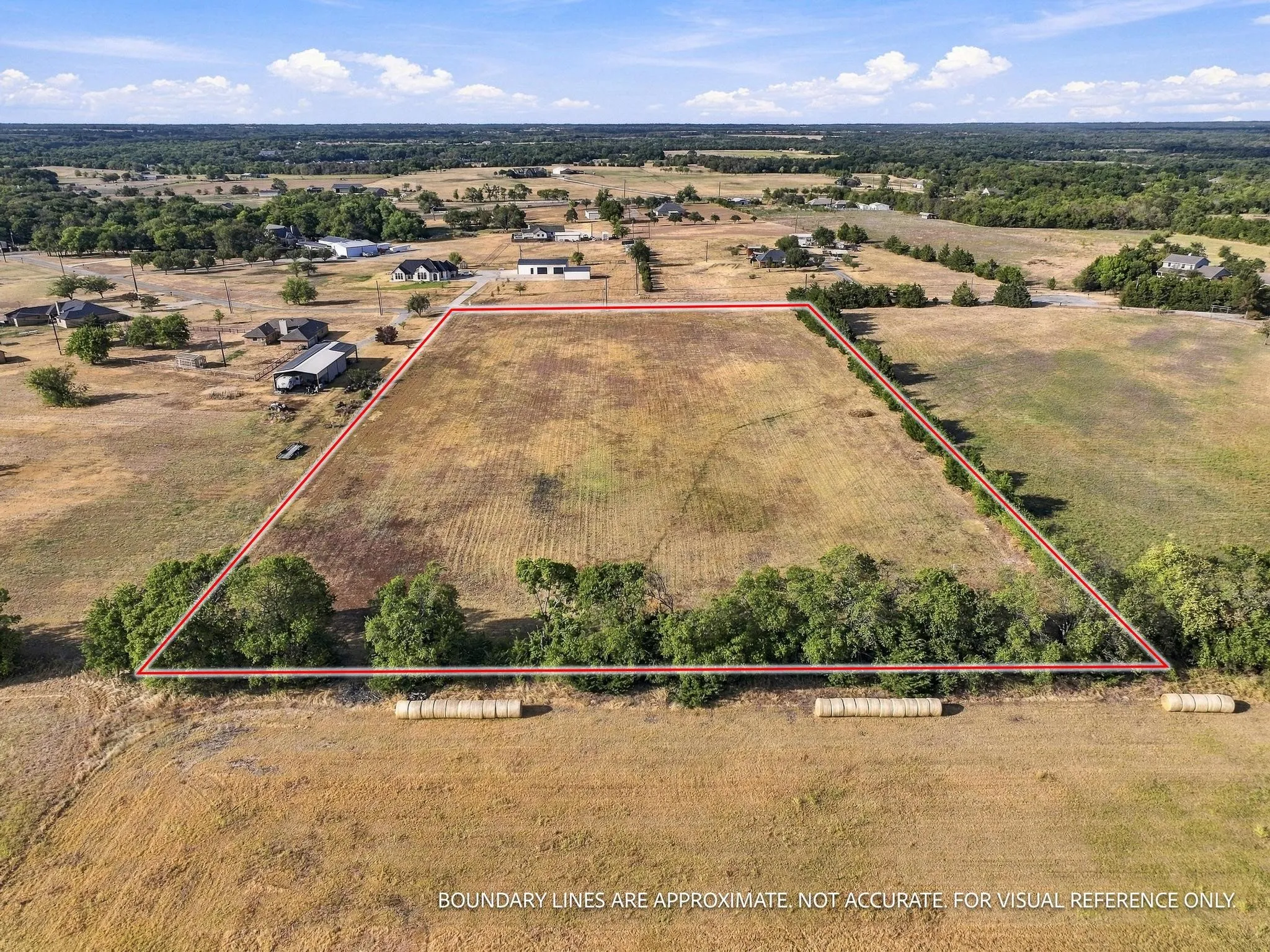 Expansive open land with perimeter trees and distant residential structures