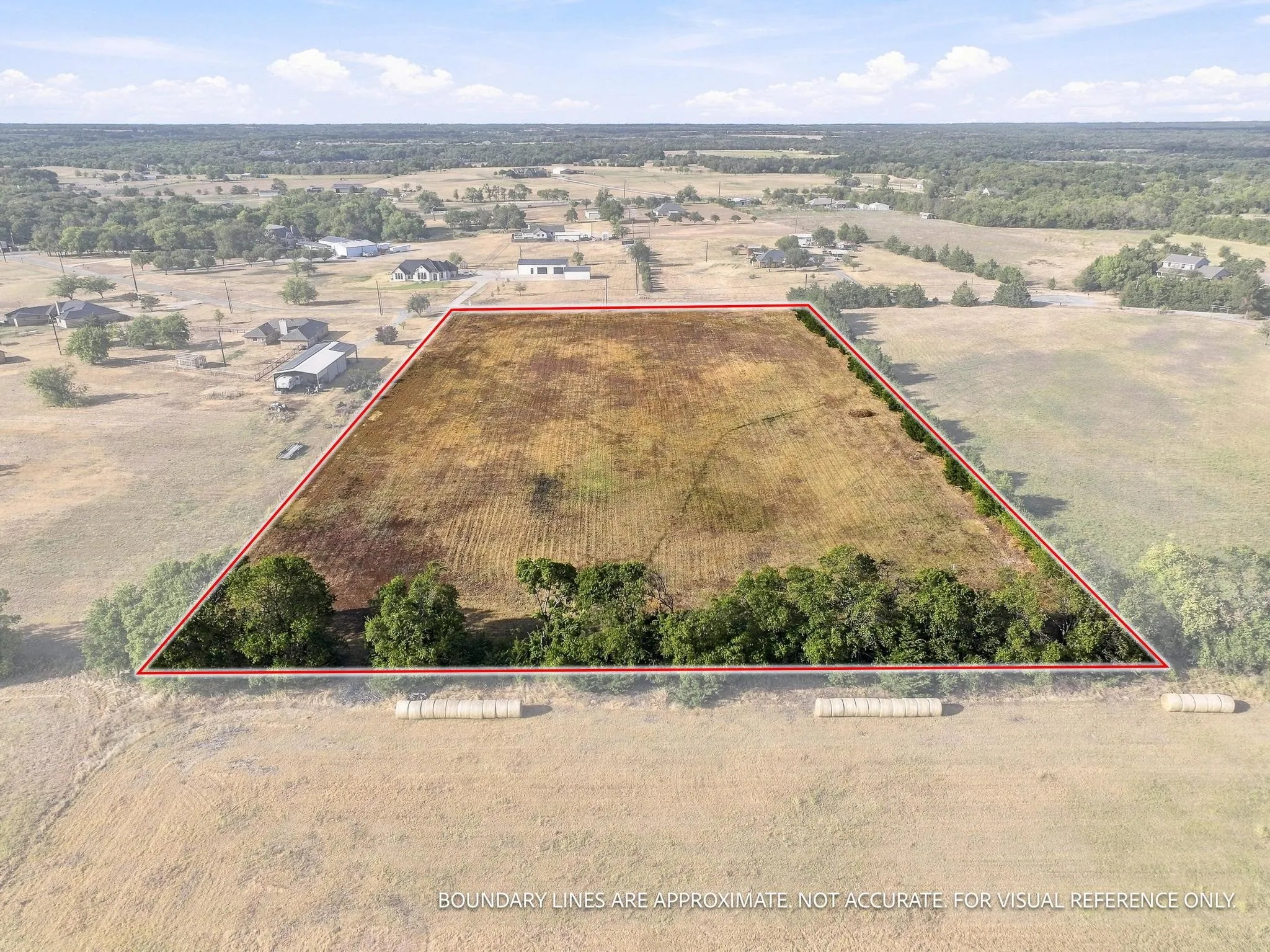 Expansive land parcel featuring a clear, open field and mature trees along the southern border