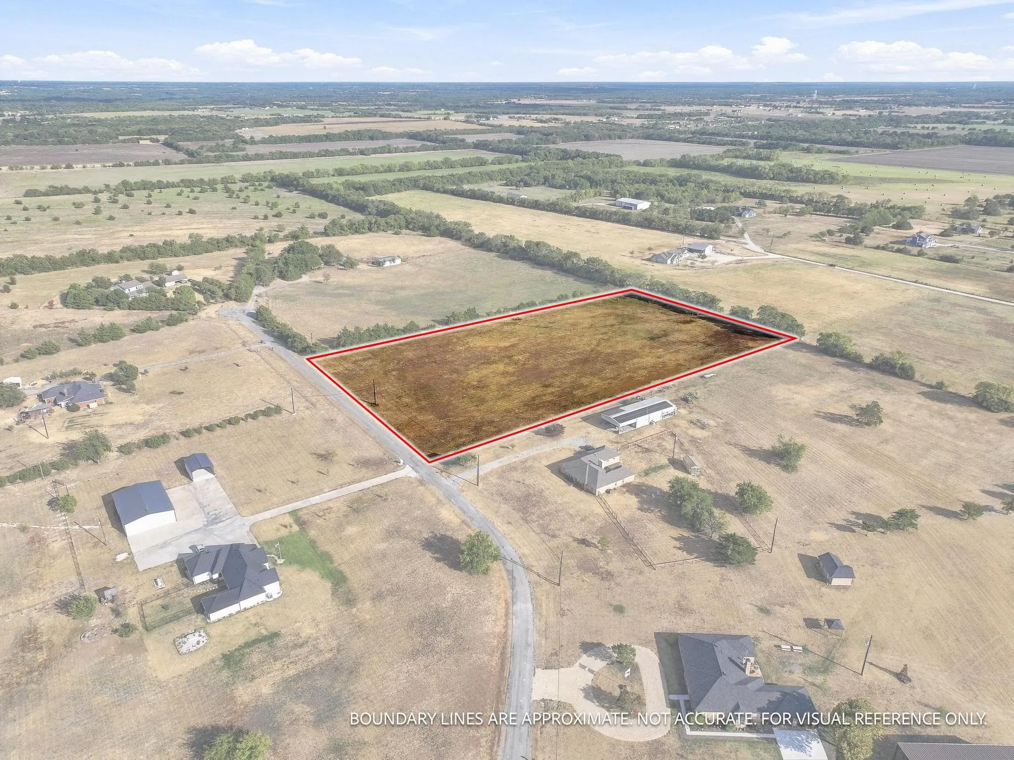 Expansive land parcel with clear boundaries, surrounded by open fields, and featuring direct road frontage