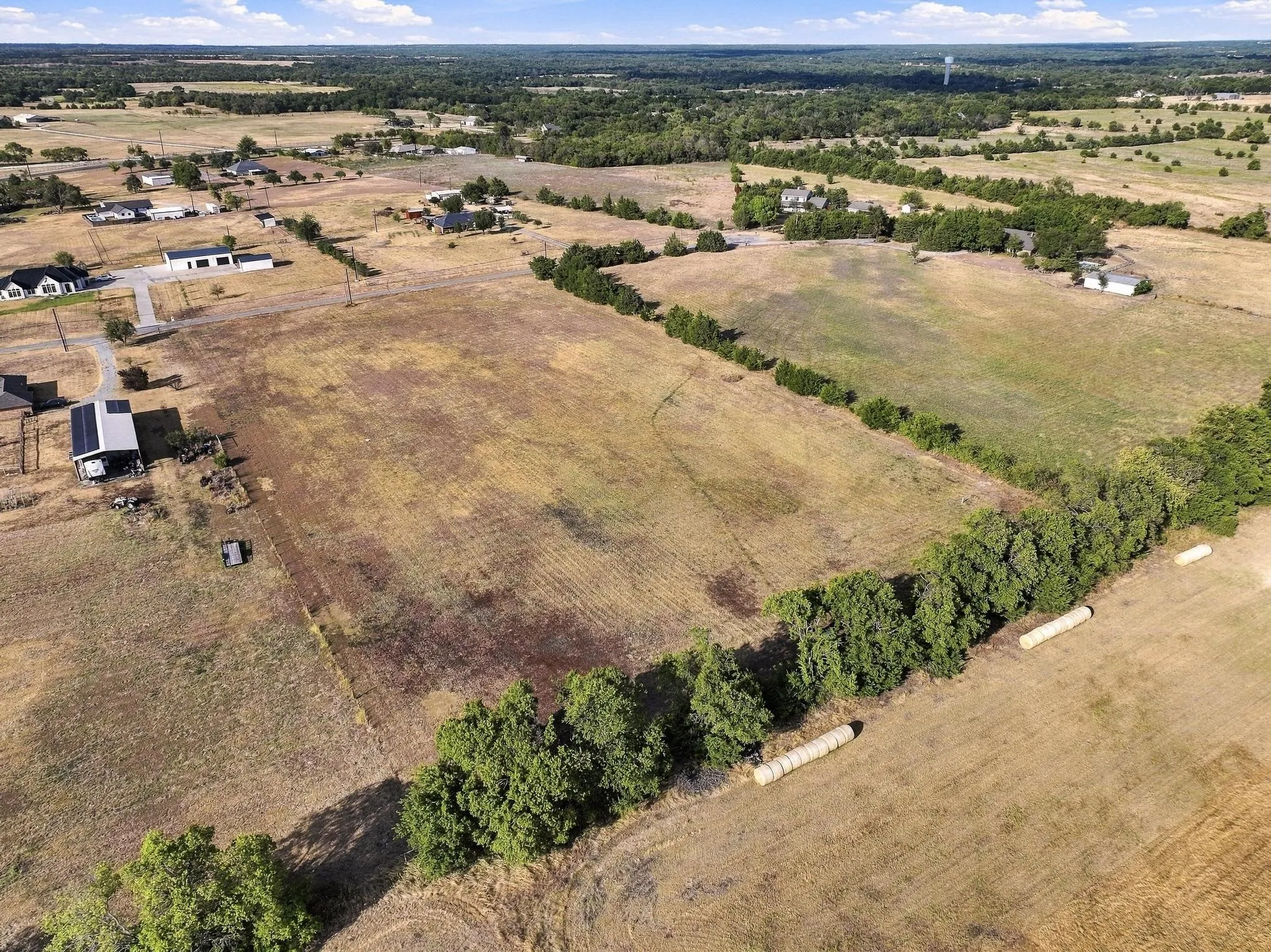 Expansive undeveloped land with a distant treeline and scattered residential structures