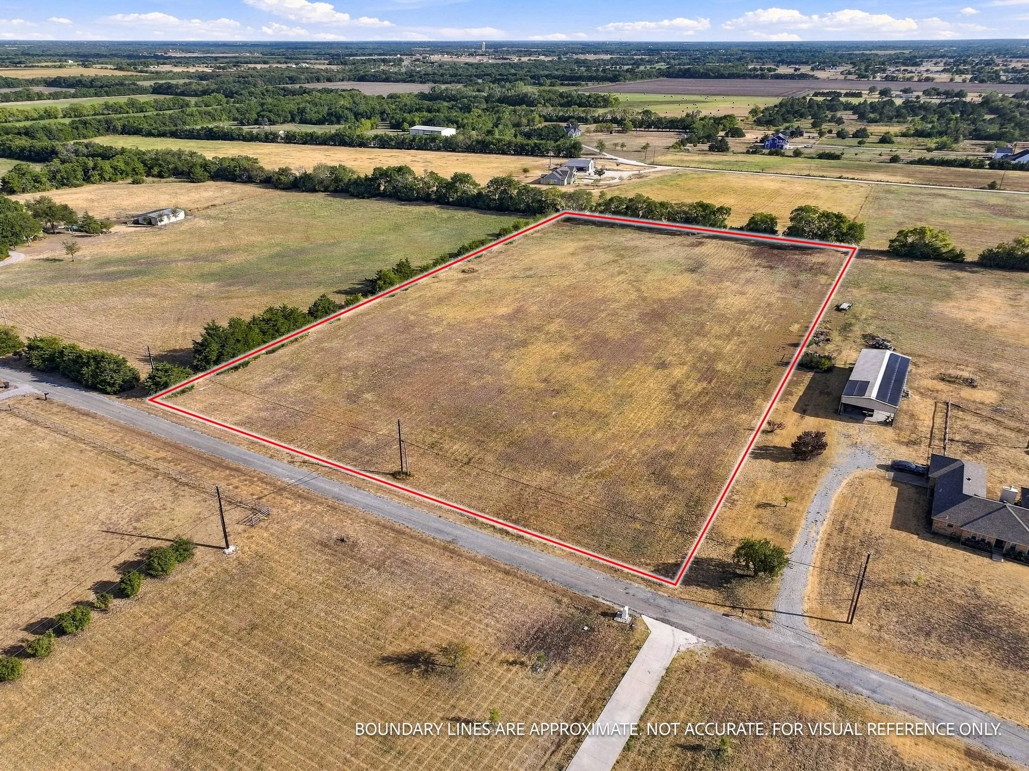 Expansive undeveloped lot with clear boundaries, bordered by mature trees and open fields