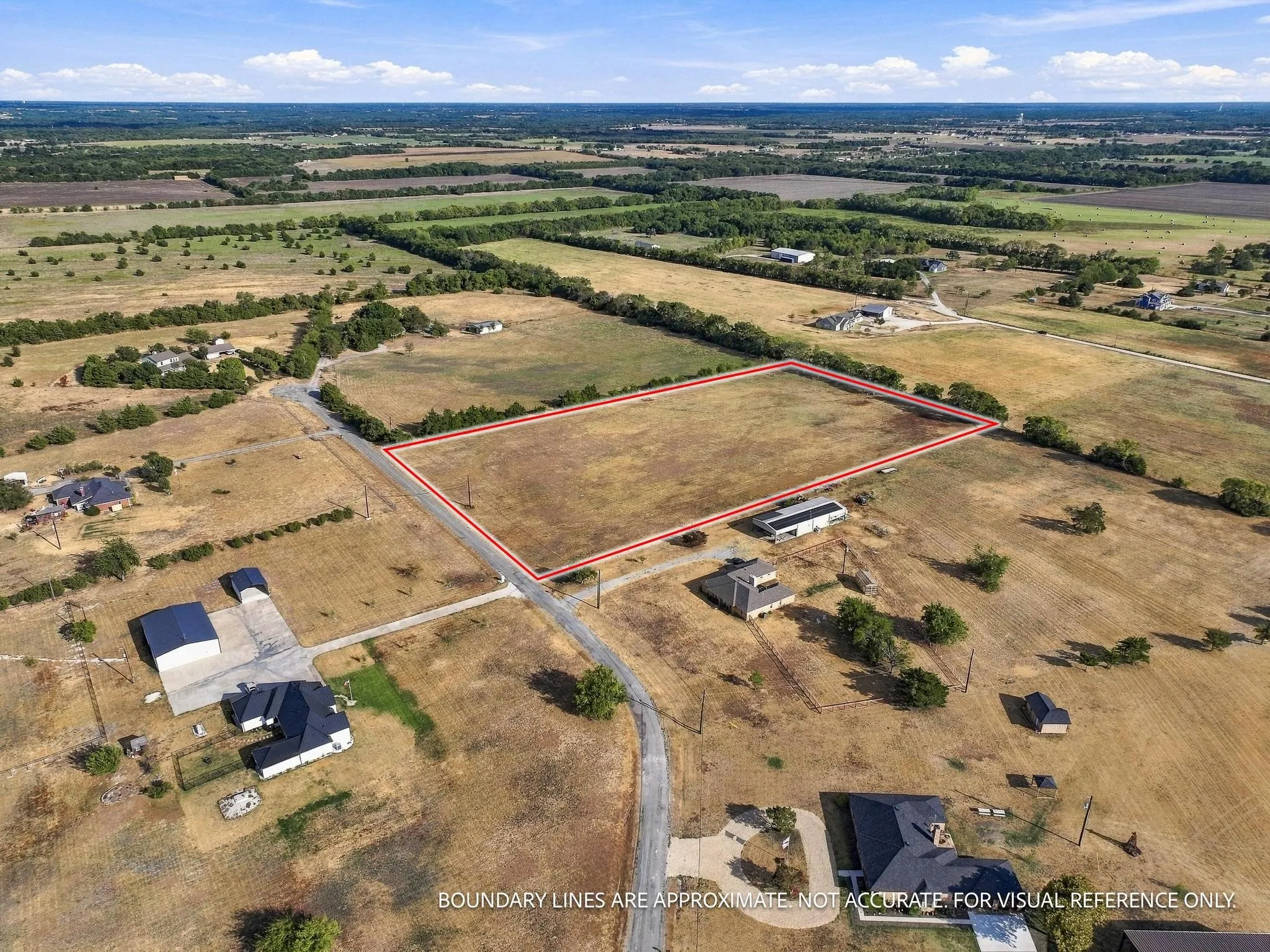 Expansive open land parcel with clear boundaries, surrounded by natural terrain and distant structures