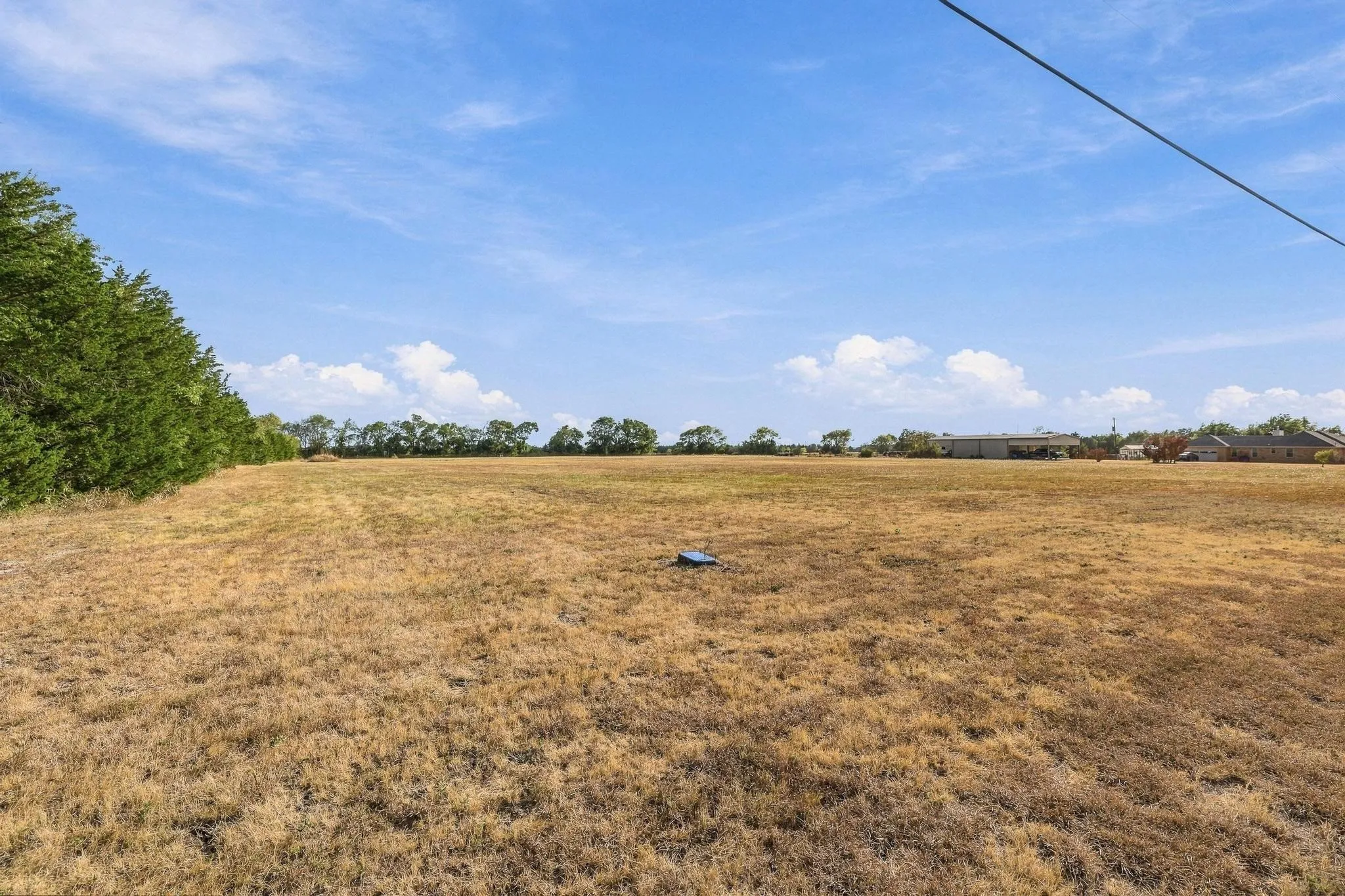 Expansive open land featuring a clear sky and distant trees