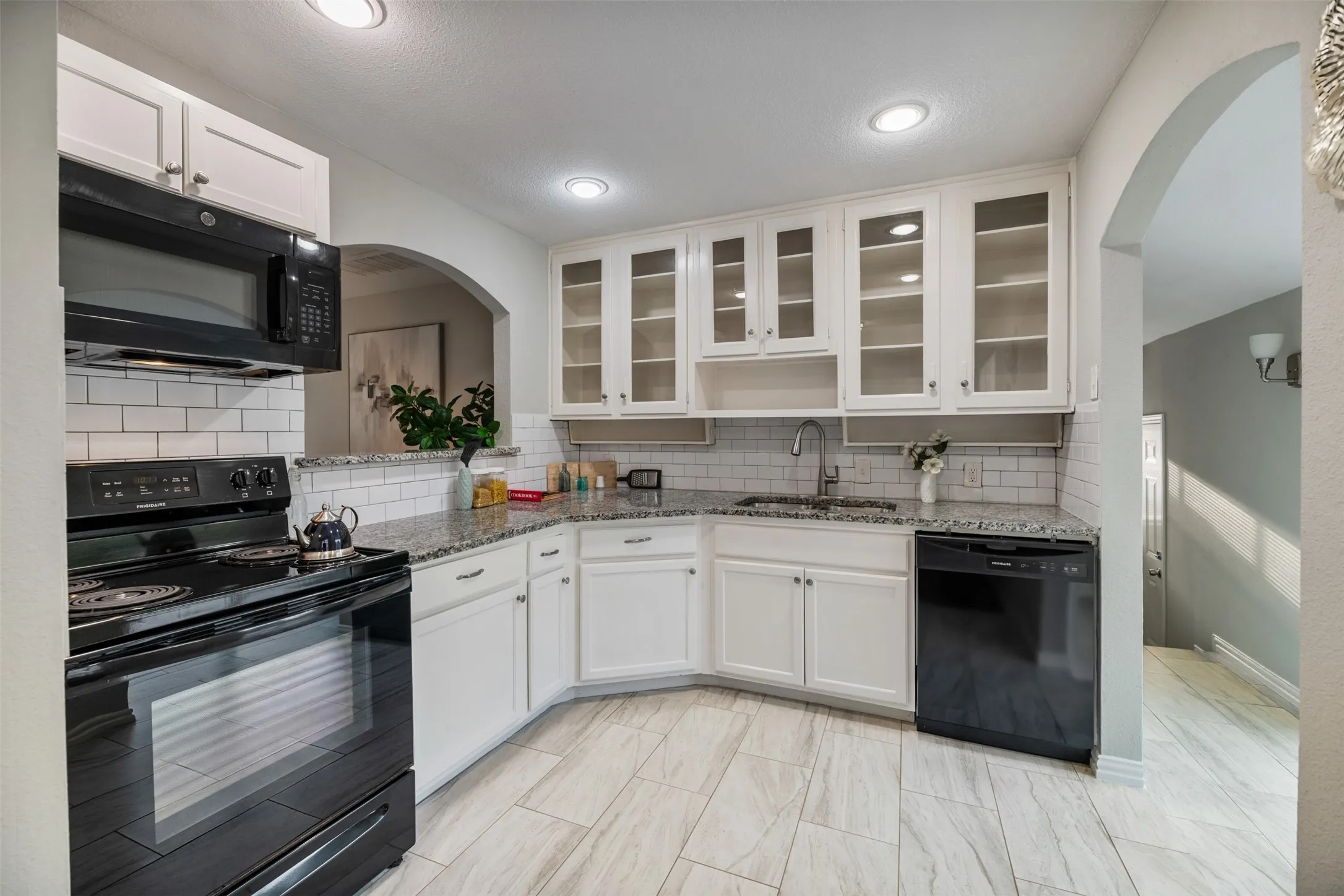 Kitchen has granite countertops, new tile floors, and attractive glass door cabinets