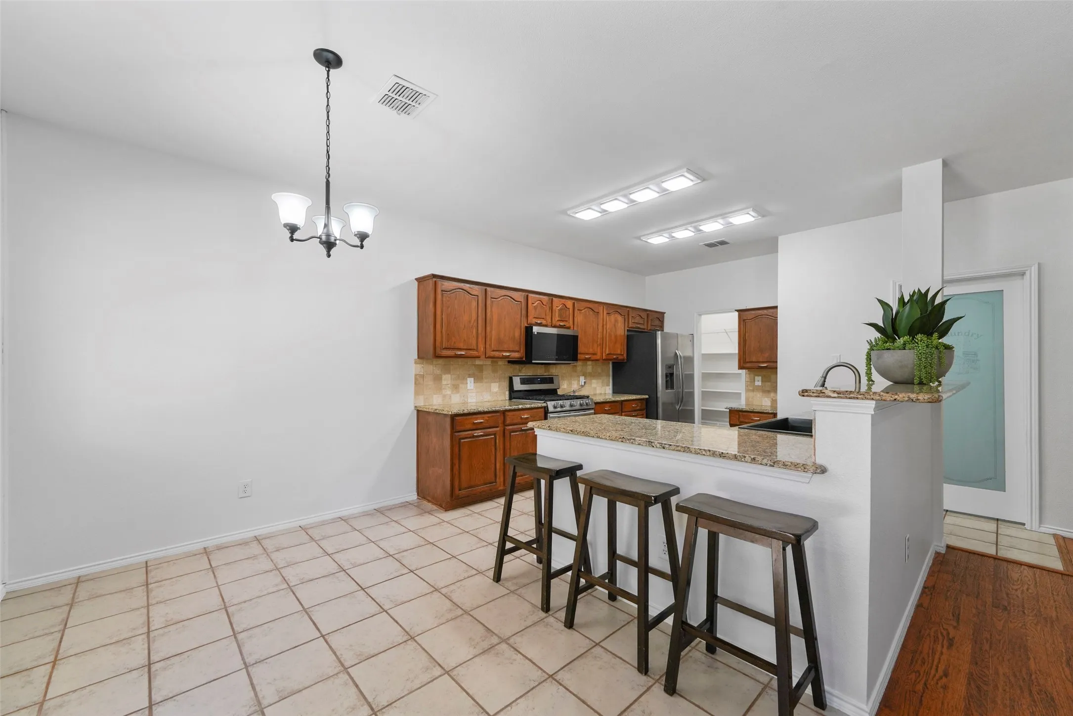 Kitchen with wood-finish cabinetry, granite countertops, and tile backsplash