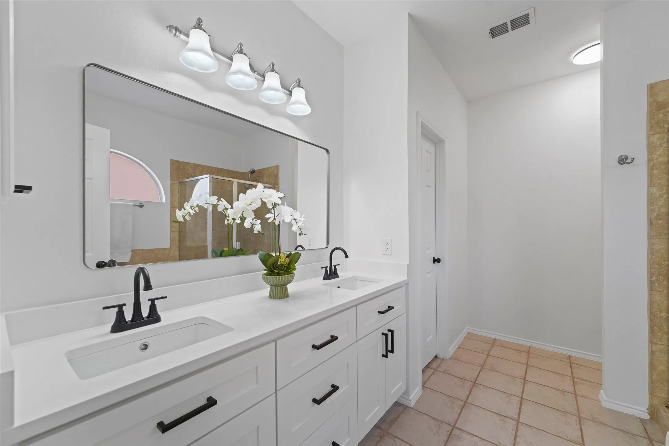 Dual vanity with white countertops, matte black faucets, and black cabinet hardware