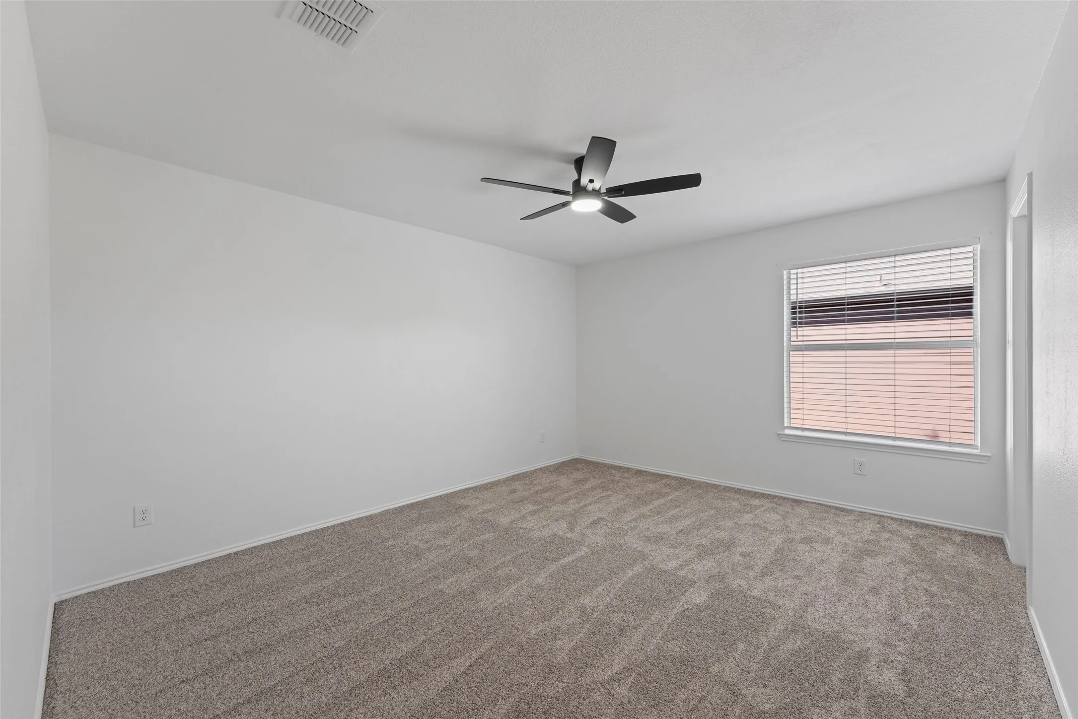 Carpeted room with a ceiling fan, a window with blinds, and white walls