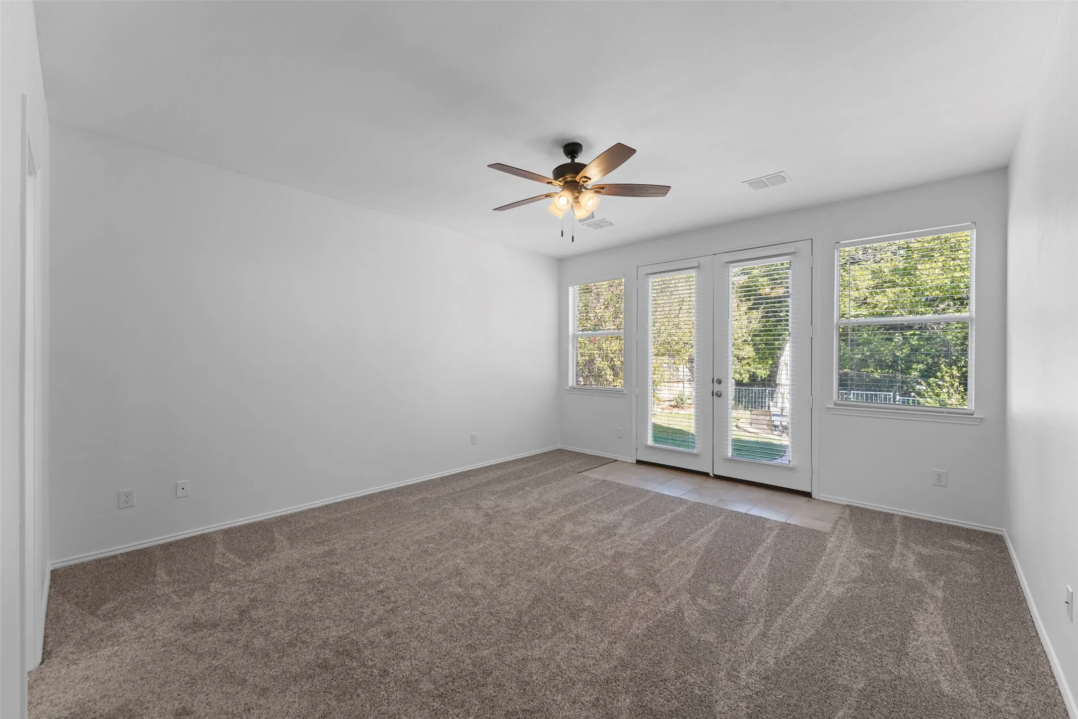 Spacious room featuring carpeting, a ceiling fan, and white walls