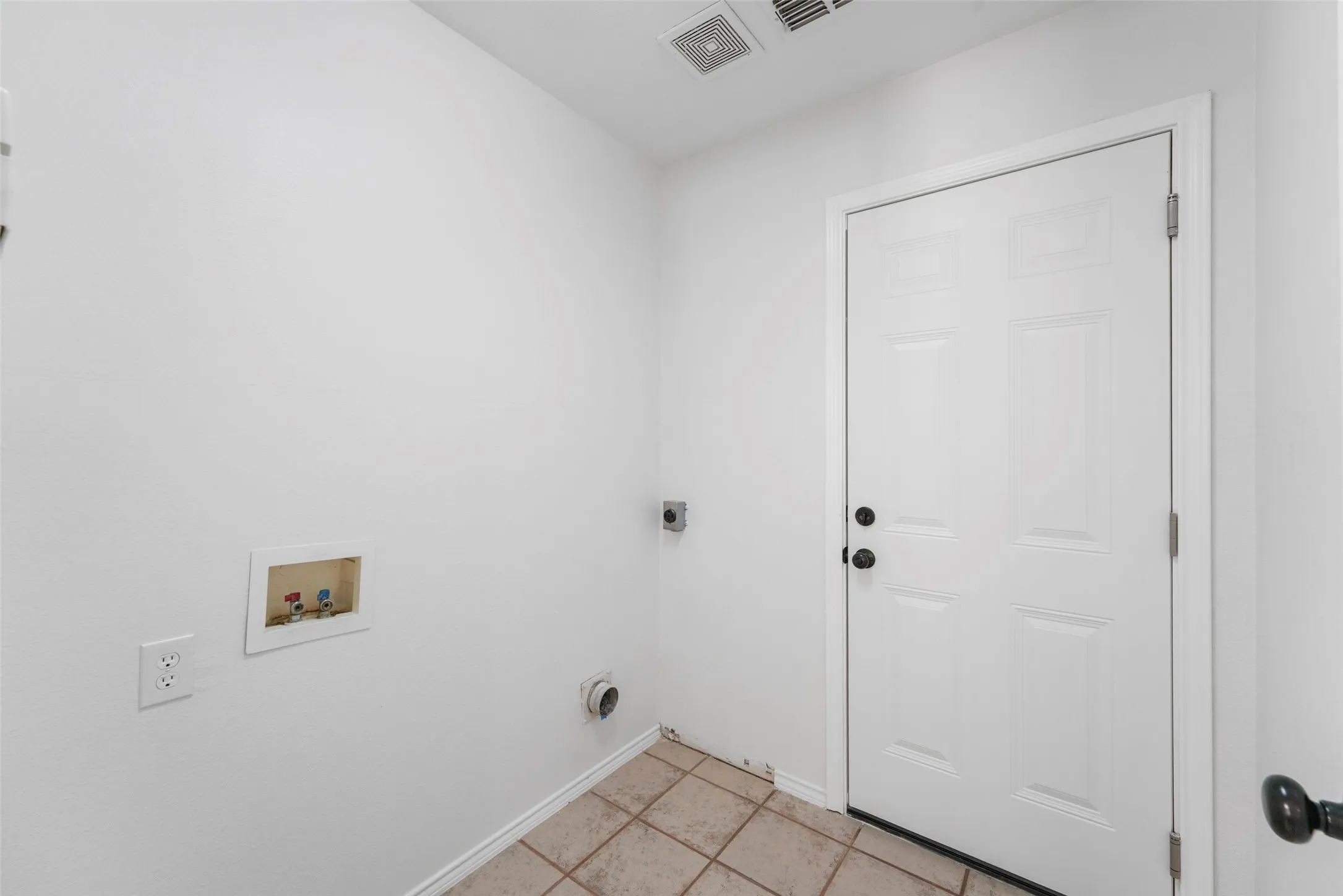 Utility space featuring tile flooring, white walls, and a paneled door