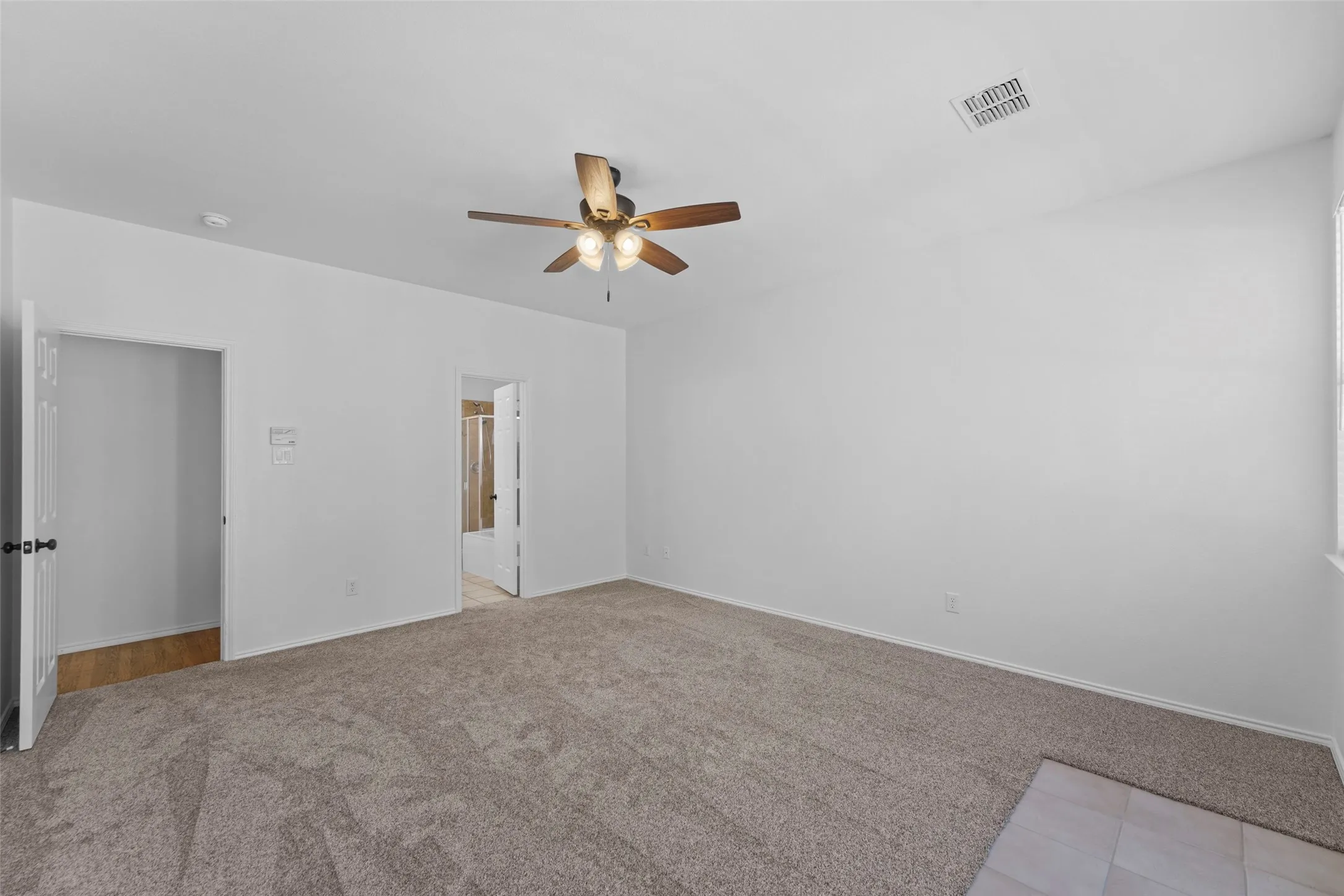 Spacious room featuring carpeting, ceiling fan with integrated lighting, and white walls