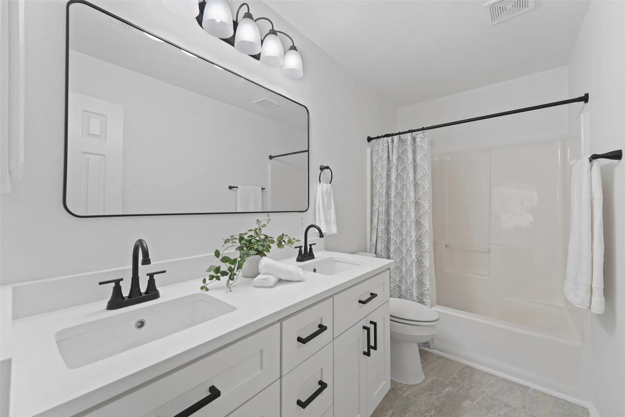 Dual vanity with white shaker cabinets and black hardware, matte black faucets, and a white countertop