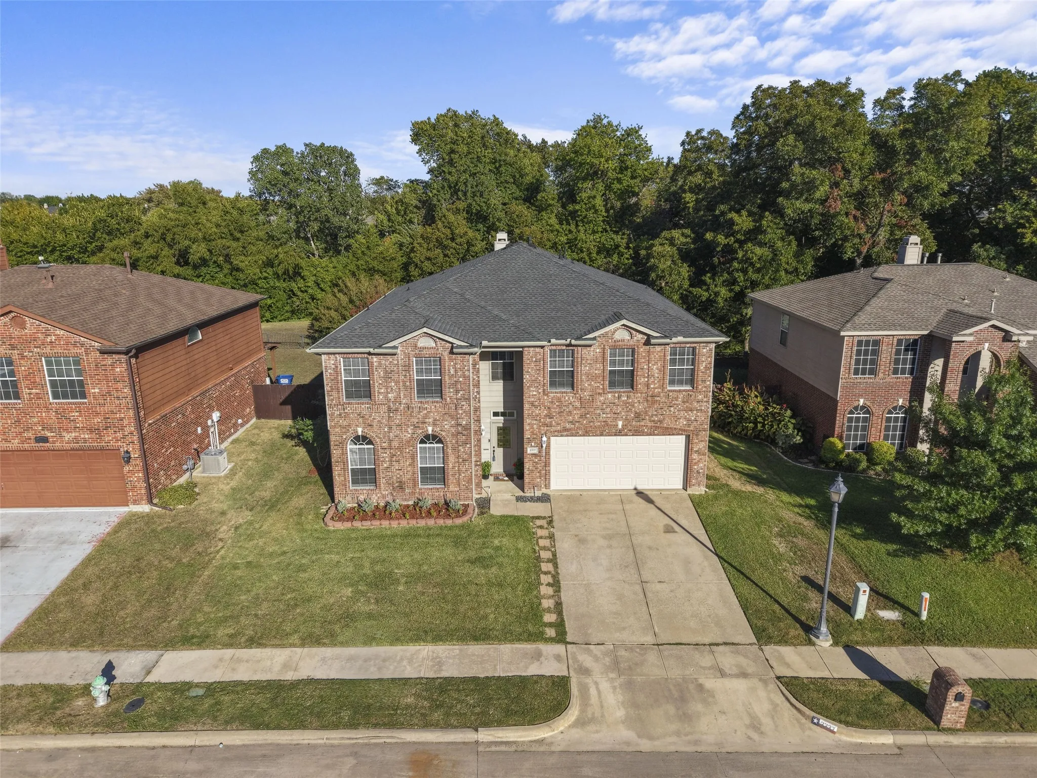 Traditional brick exterior with an attached garage, dormer windows, and a concrete driveway