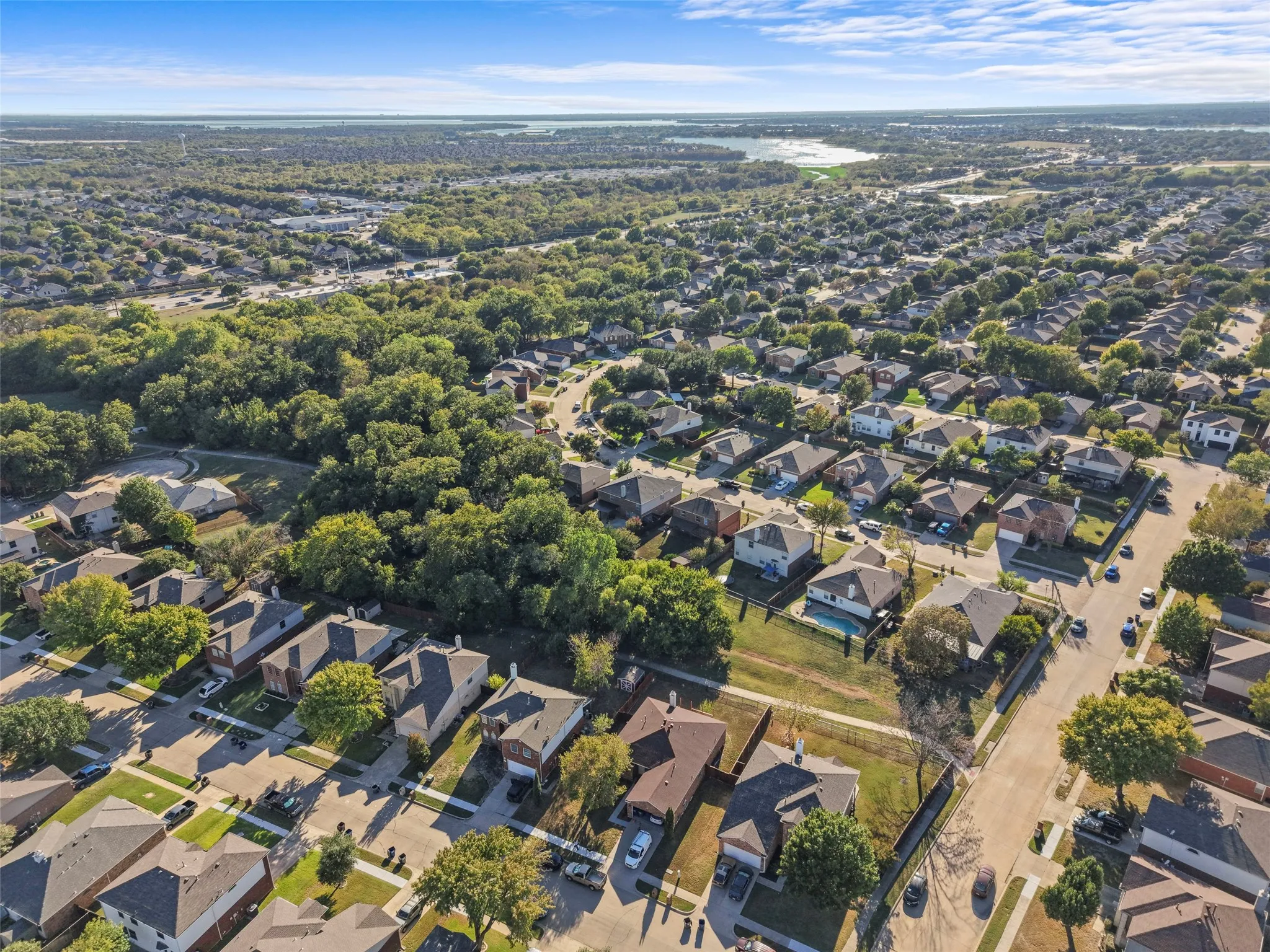 Aerial view of a residential community with abundant mature trees and a distant body of water