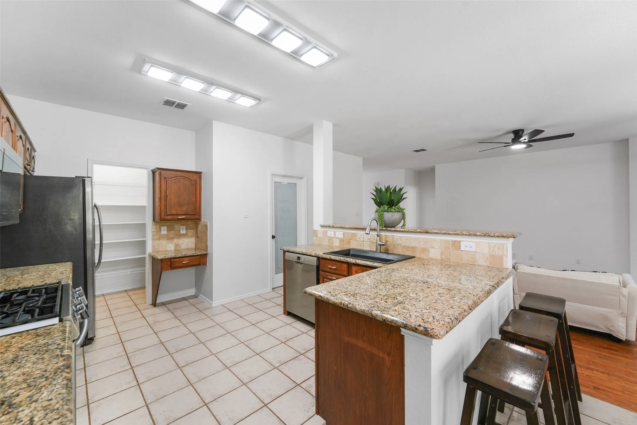 Kitchen featuring granite countertops, a gas range, stainless steel dishwasher, and a pantry with built-in shelving