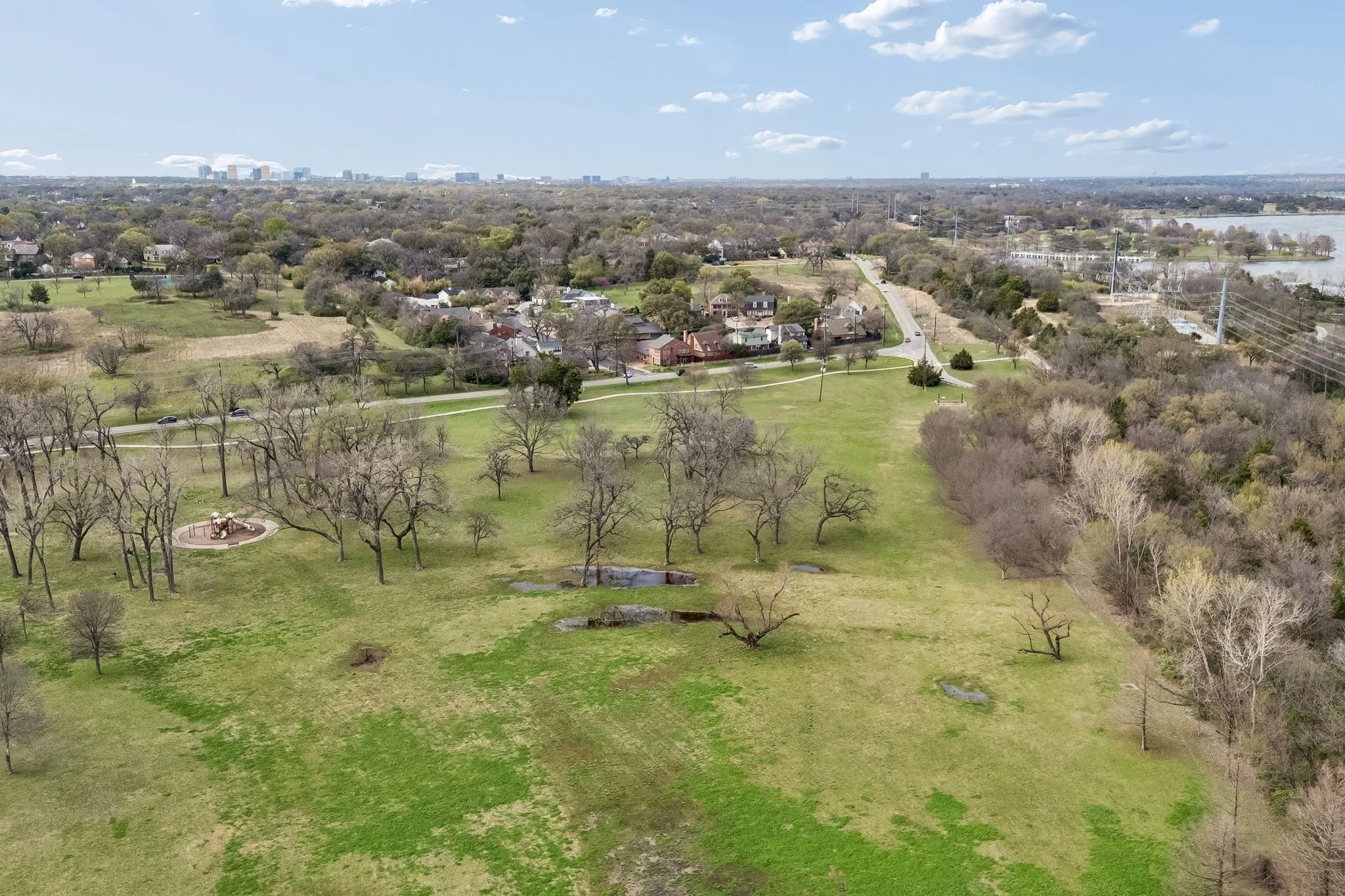 Bird's eye view of White Rock Lake, showcasing the expansive green spaces of the surrounding parks and winding trails.