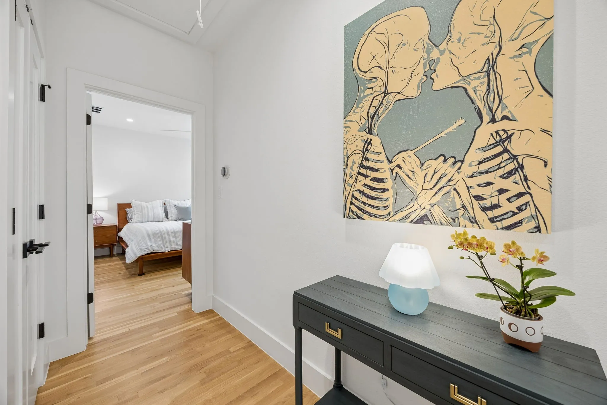 Hallway featuring light wood finished floors separating the primary and guest suite with vaulted ceiling. The spacious hallway provides easy access and a welcoming transition between the main living areas and the private suites.