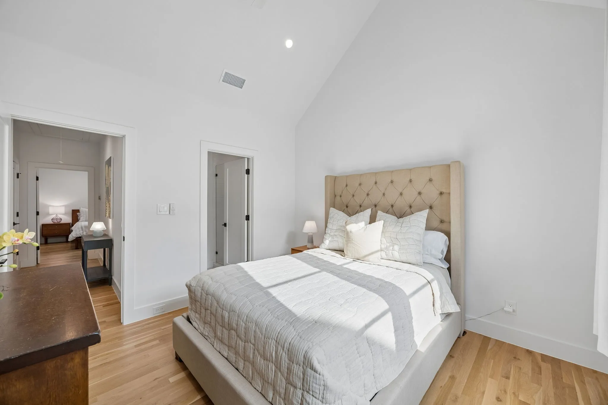 Bedroom with vaulted ceiling, light oak wood flooring, recessed lighting and ample light.