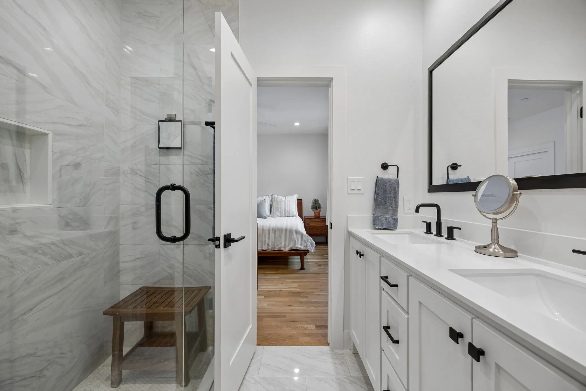 Bathroom with double vanity, ensuite bathroom, a marble finish shower, and light marble finish floors