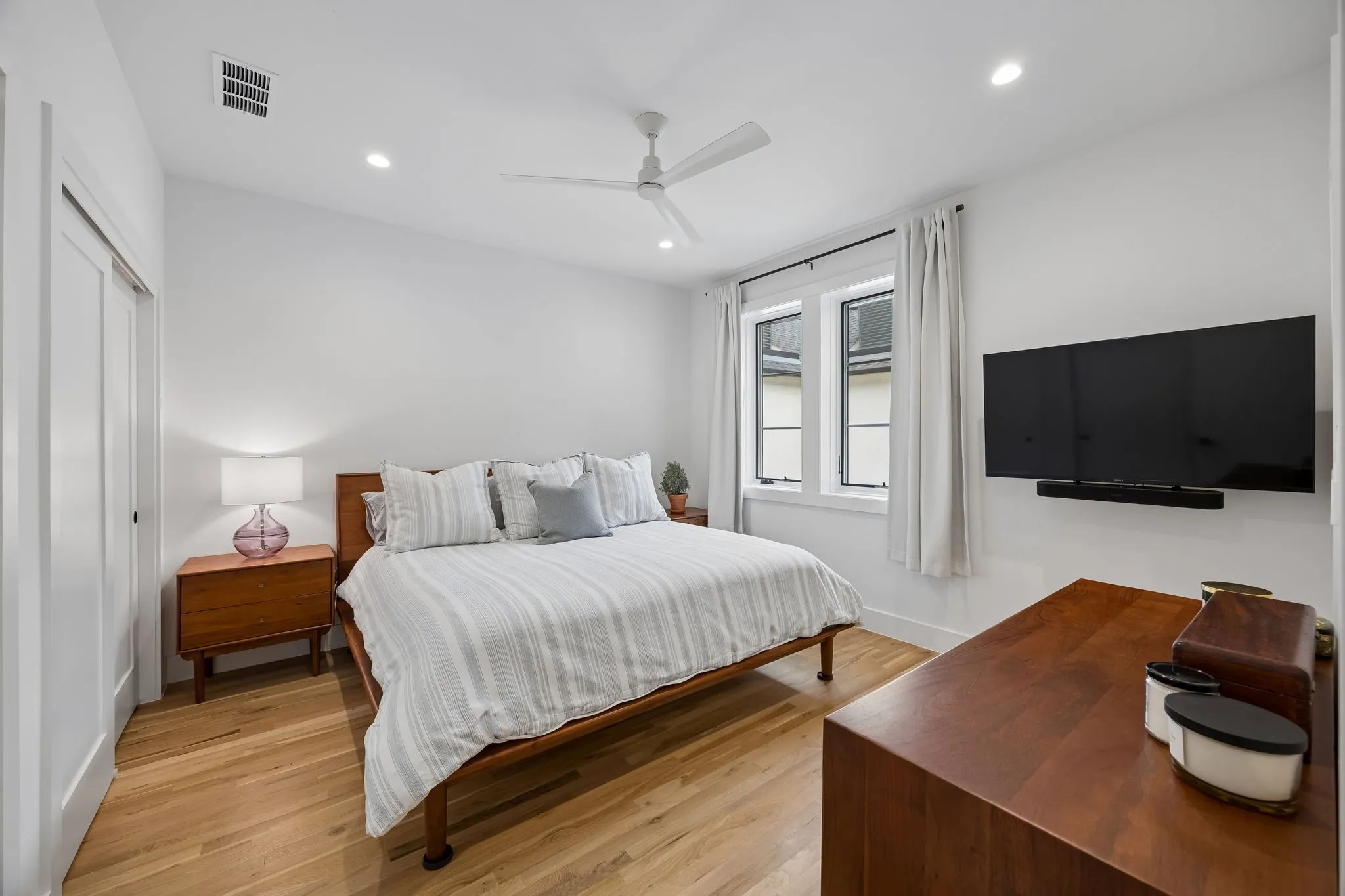 Bedroom featuring light oak wood flooring, recessed lighting, a ceiling fan, and a dual closet system.