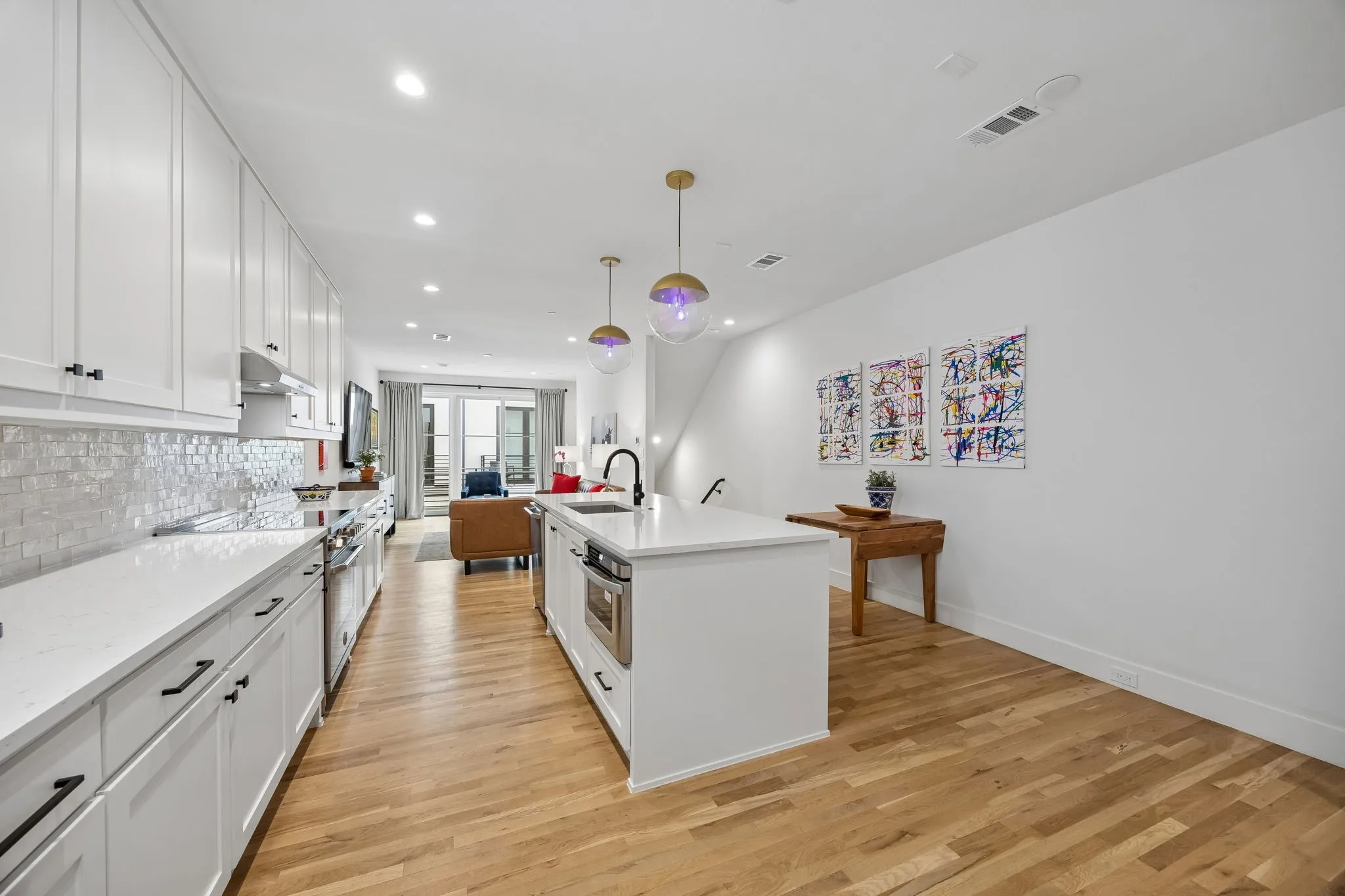 Kitchen featuring white cabinetry, light oak wood flooring, a center island with built-in appliances, and a tiled backsplash