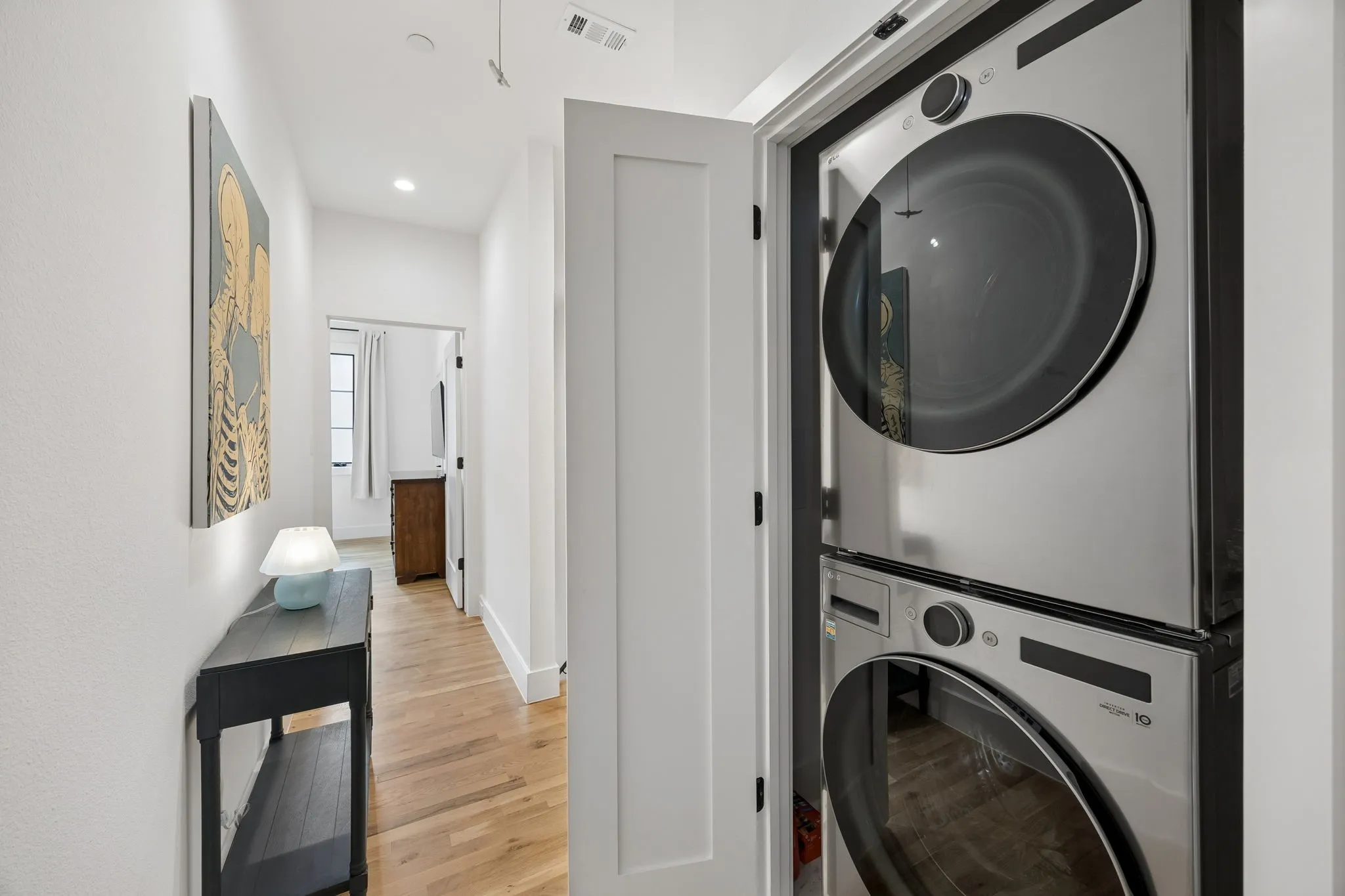Laundry Room: This area features a stacked washer and dryer, light oak wood-finished floors, and is conveniently located between the two bedrooms.