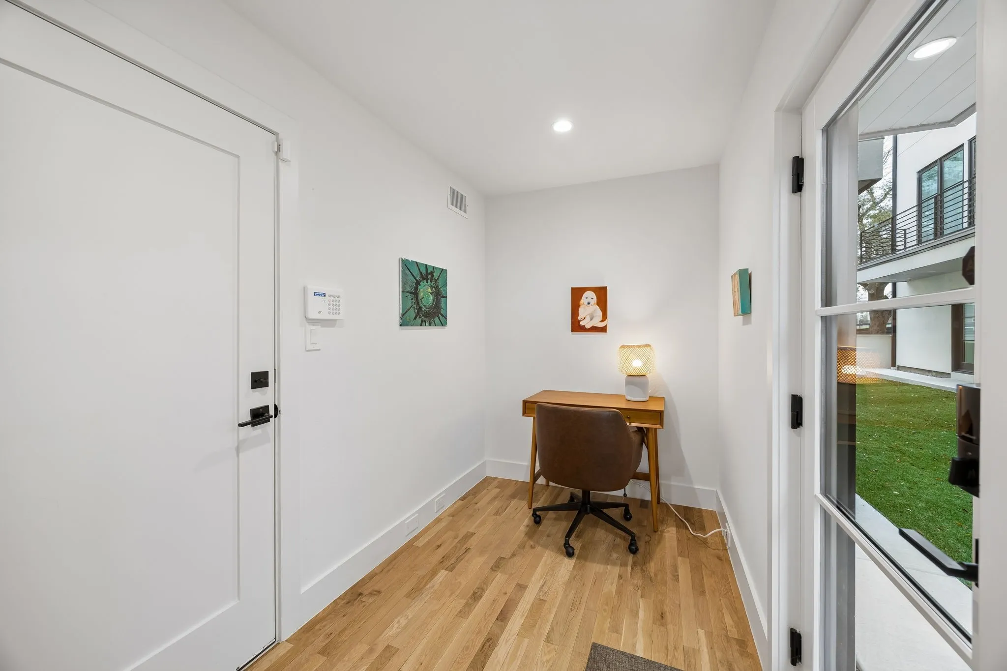 Front entry landing with light oak wood-finished flooring and recessed lighting, offering a convenient drop zone for personal items.