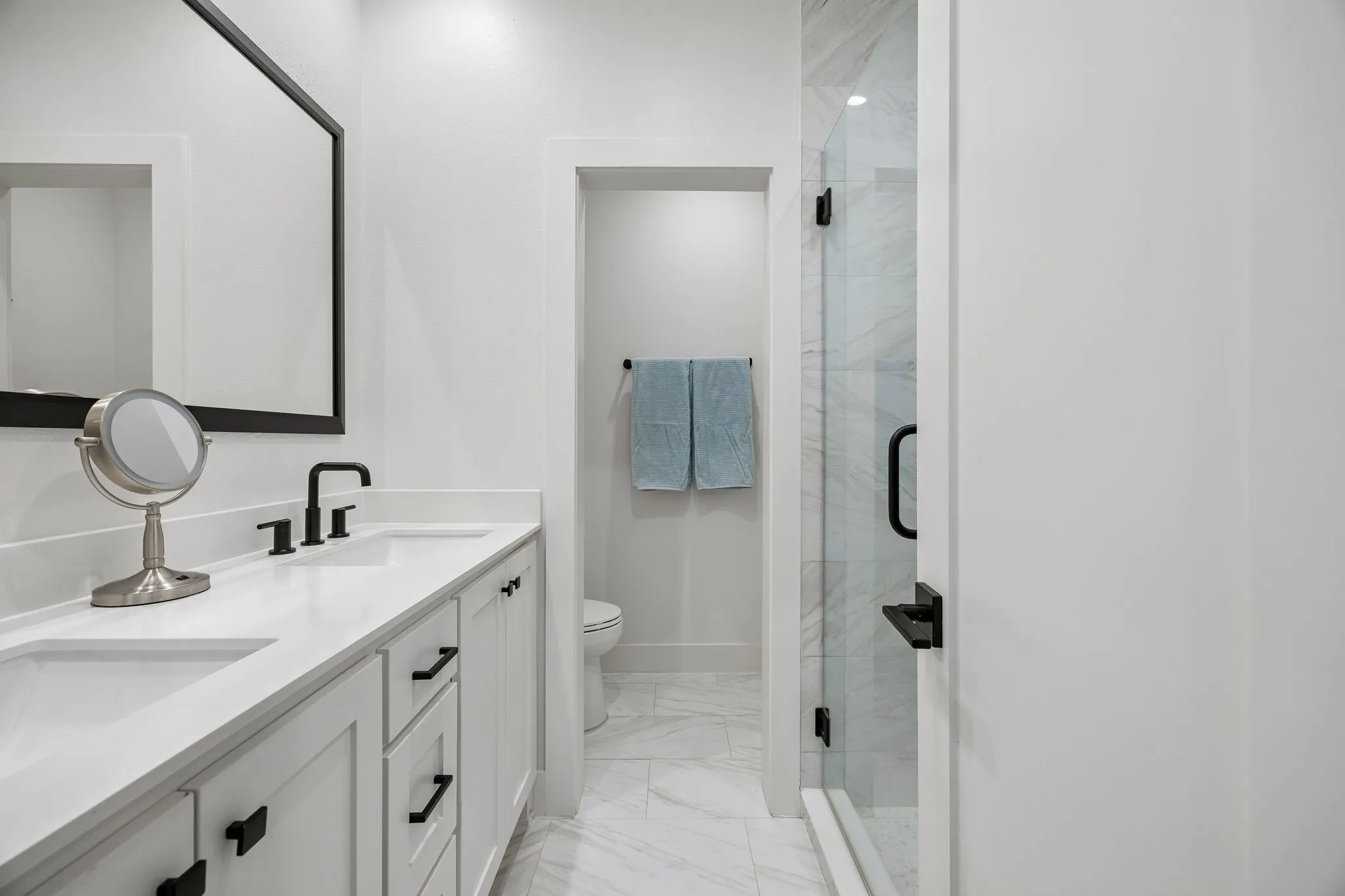 Bathroom with double vanity, a walk-in shower stall, and light stone finish flooring