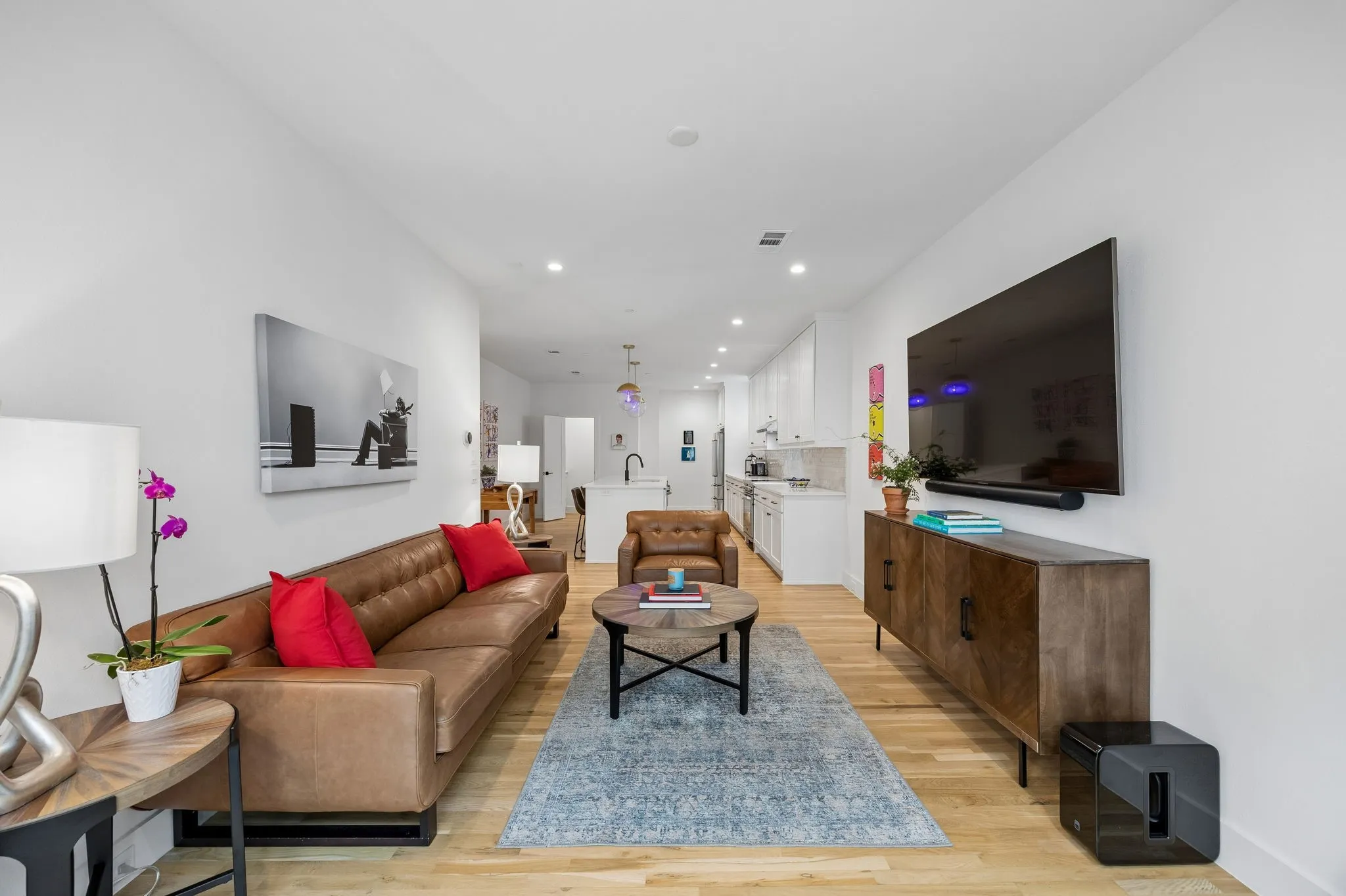 Bright and inviting living area looking back into the open kitchen space. This description highlights the key features of the photo, emphasizing the open concept and the welcoming atmosphere of the space. It paints a picture of a comfortable and functional living area seamlessly connected to the kitchen....