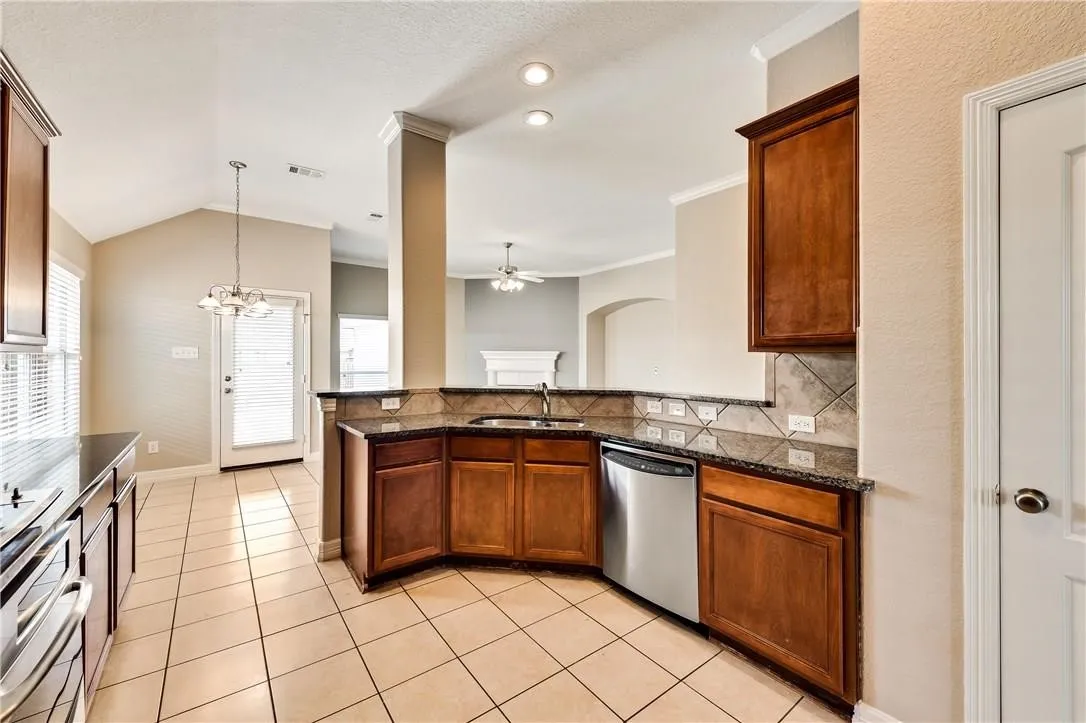 Kitchen featuring wood cabinetry, dark countertops, a tile backsplash, and stainless steel appliances